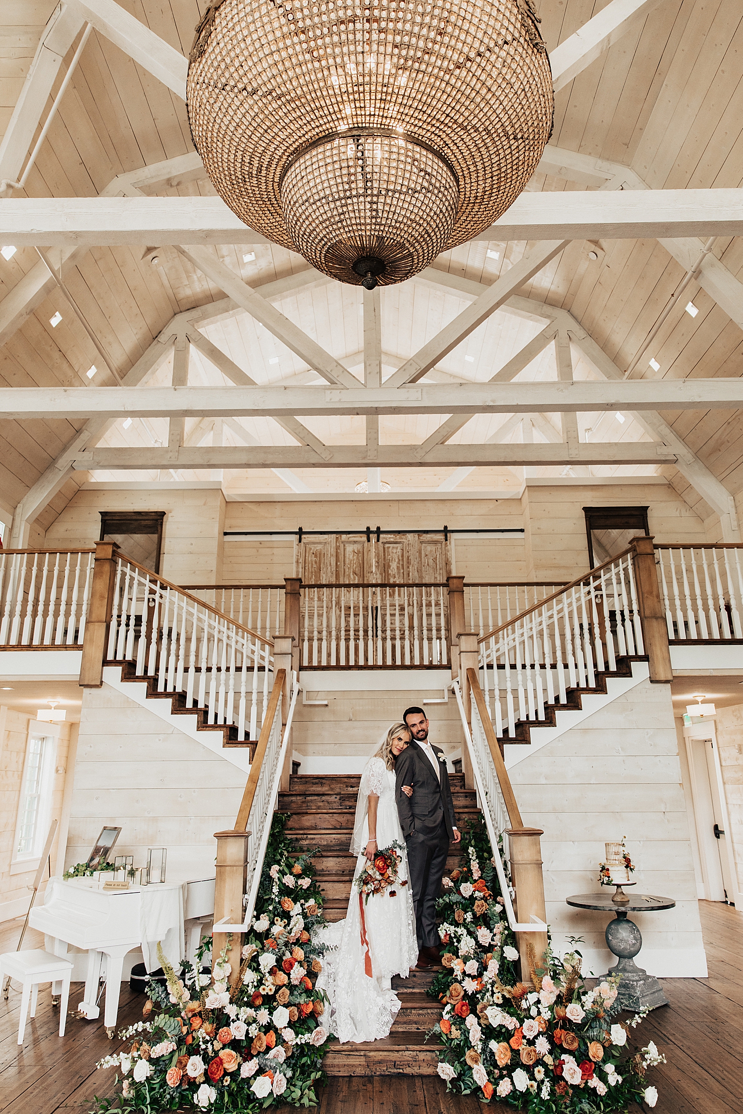 newlyweds stand at bottom of stairs surrounded by florals by Destination wedding photographer