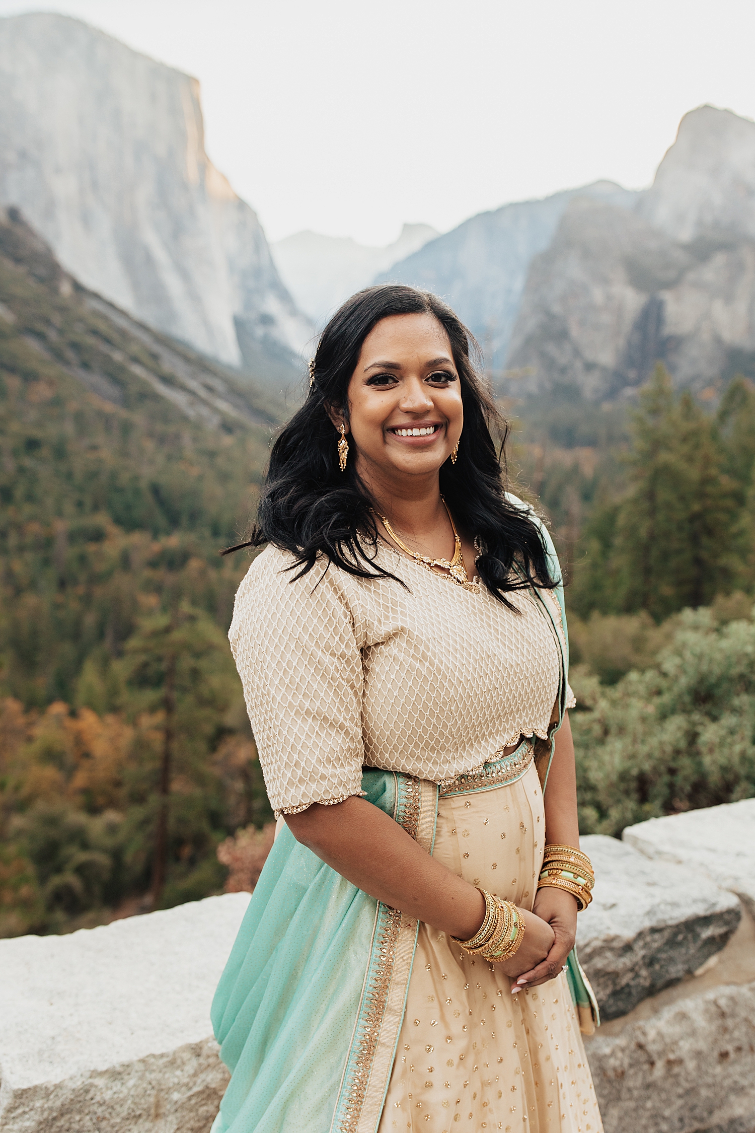 bride-to-be in traditional Indian clothing stands in front of mountain backdrop by Nicole Aston Photography