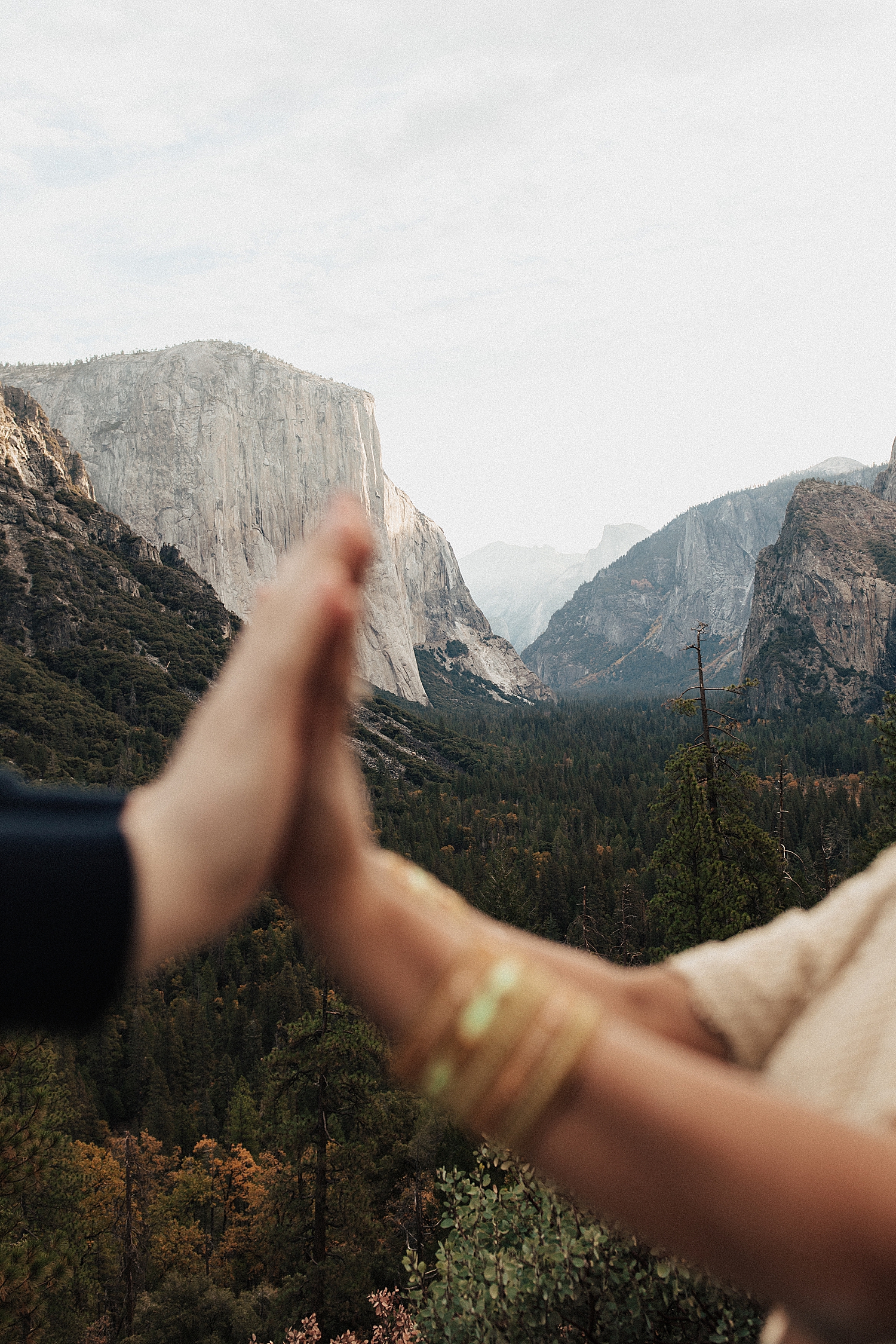 man and woman put their hands together with mountains in distance by Destination wedding photographer