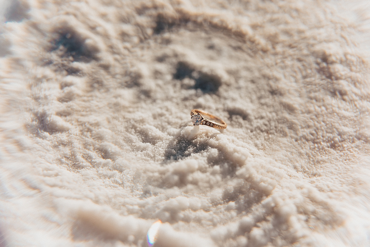 gold and diamond ring sitting on bed of salt by Nicole Aston Photography