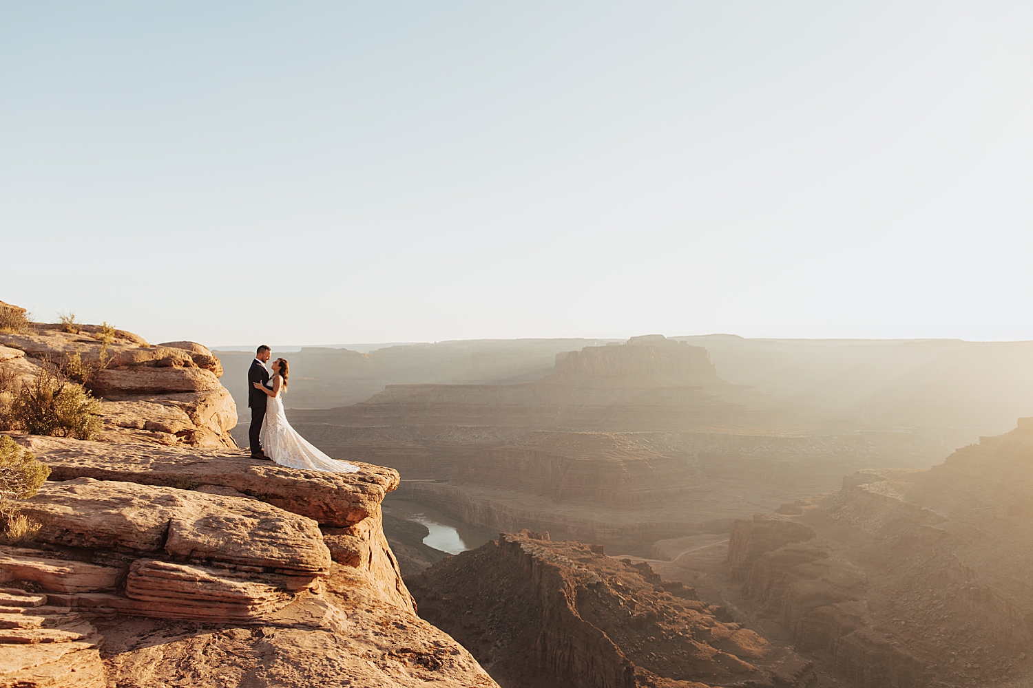 husband and wife stand cliffside looking over canyon for Moab Micro Wedding