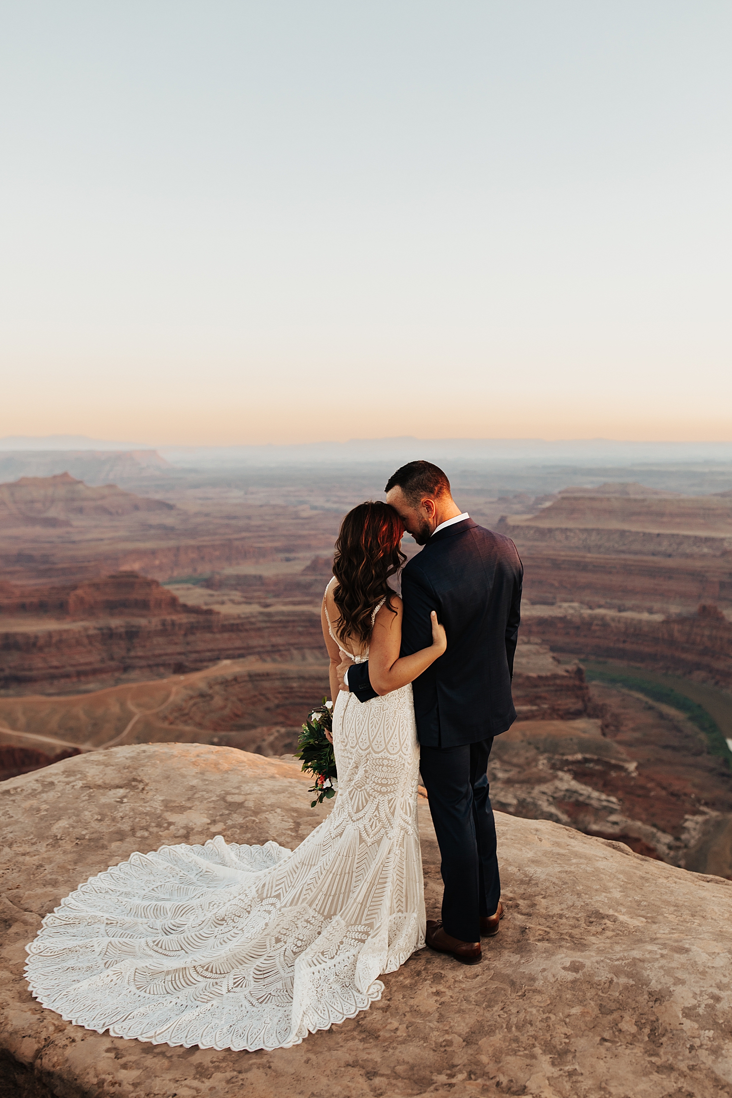 newlyweds snuggle close overlooking epic canyon for Moab Micro Wedding