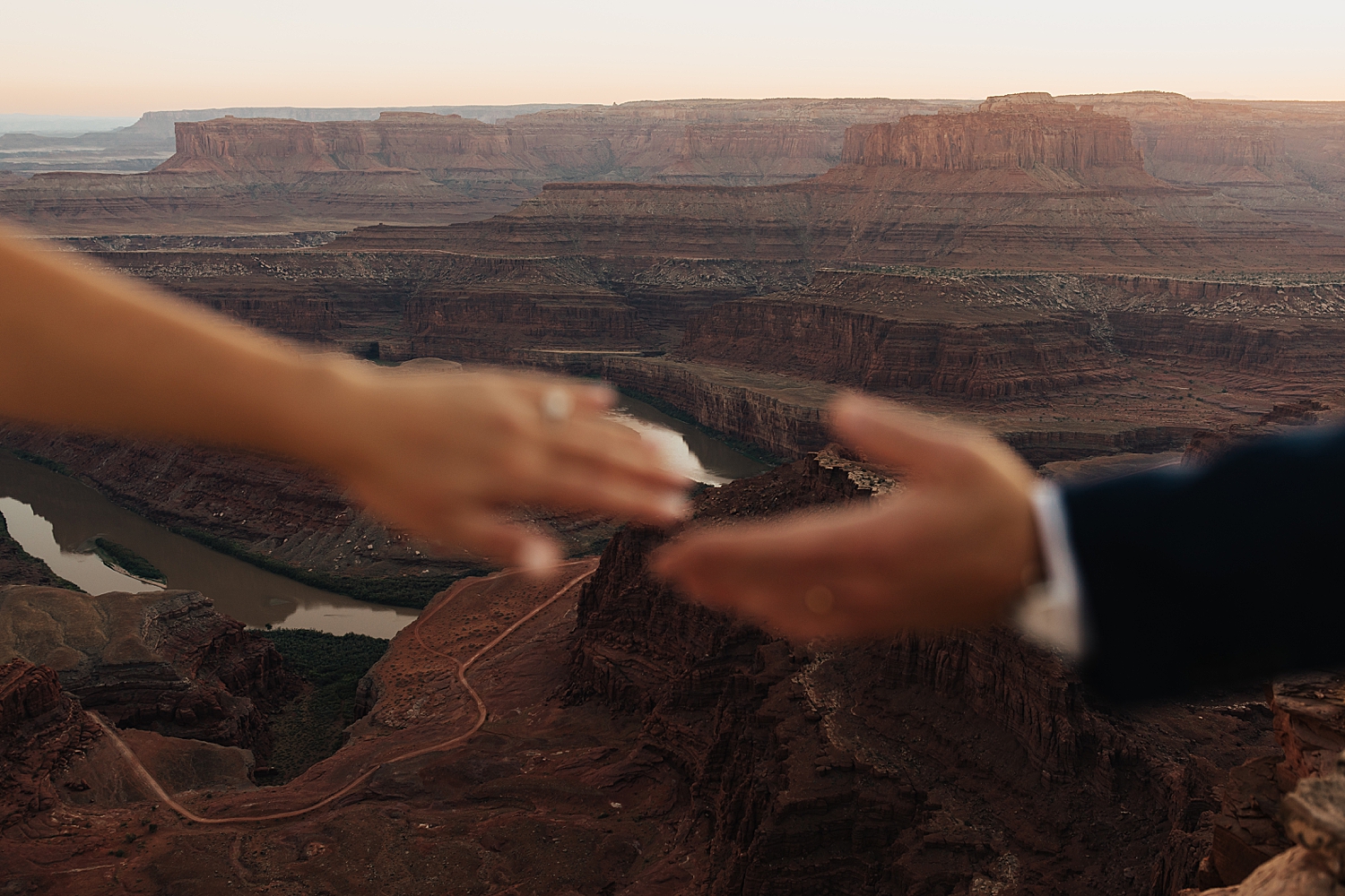 two hands reach for each other with canyon in the background by Destination elopement photographer
