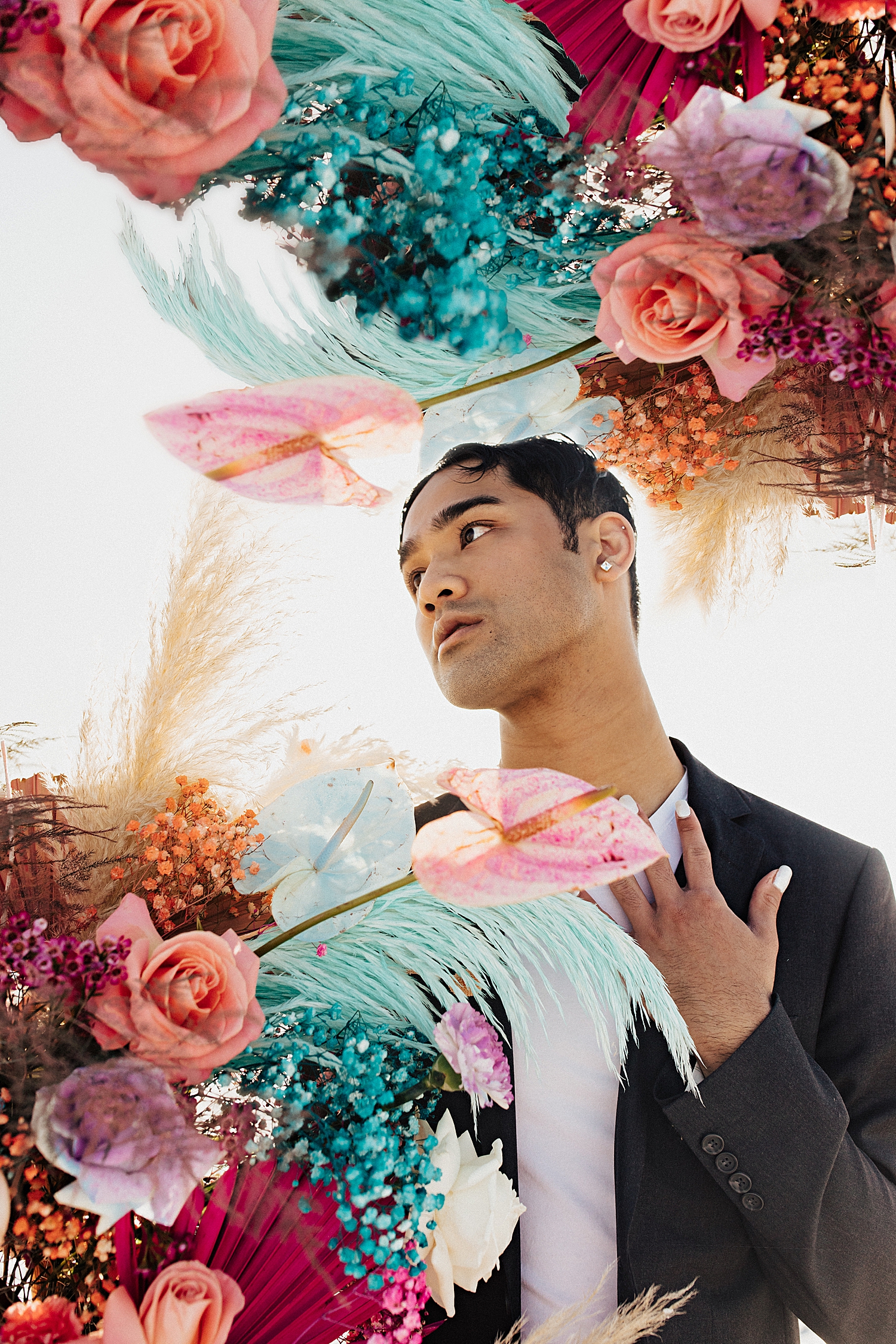 model in charcoal suit surrounded by colorful flowers for styled session with sweet afton floral