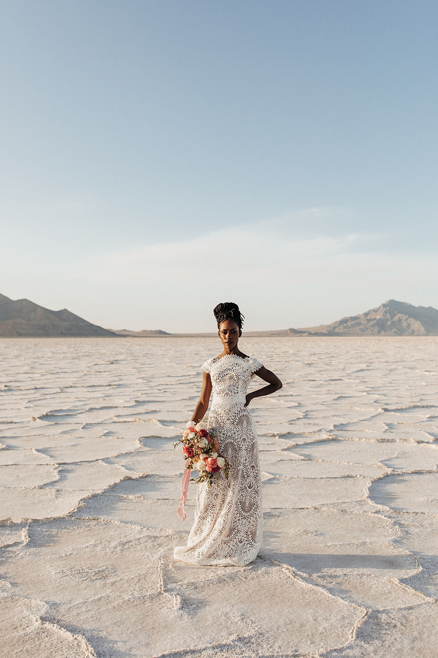 woman with custom lace bridal gown stands on salt flats by Nicole Aston Photography