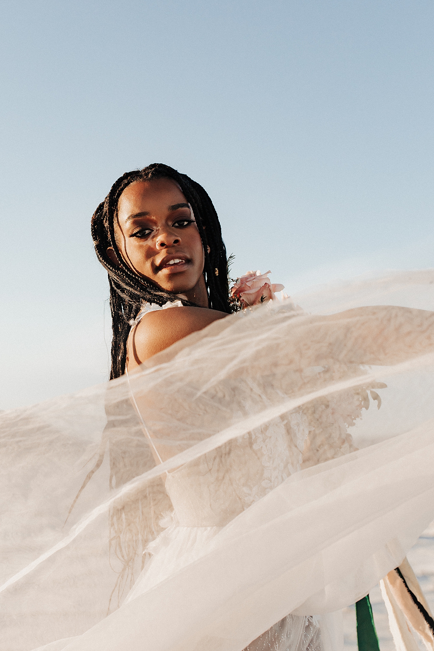 bride in dessert wipes her veil in the wind by Destination wedding photographer