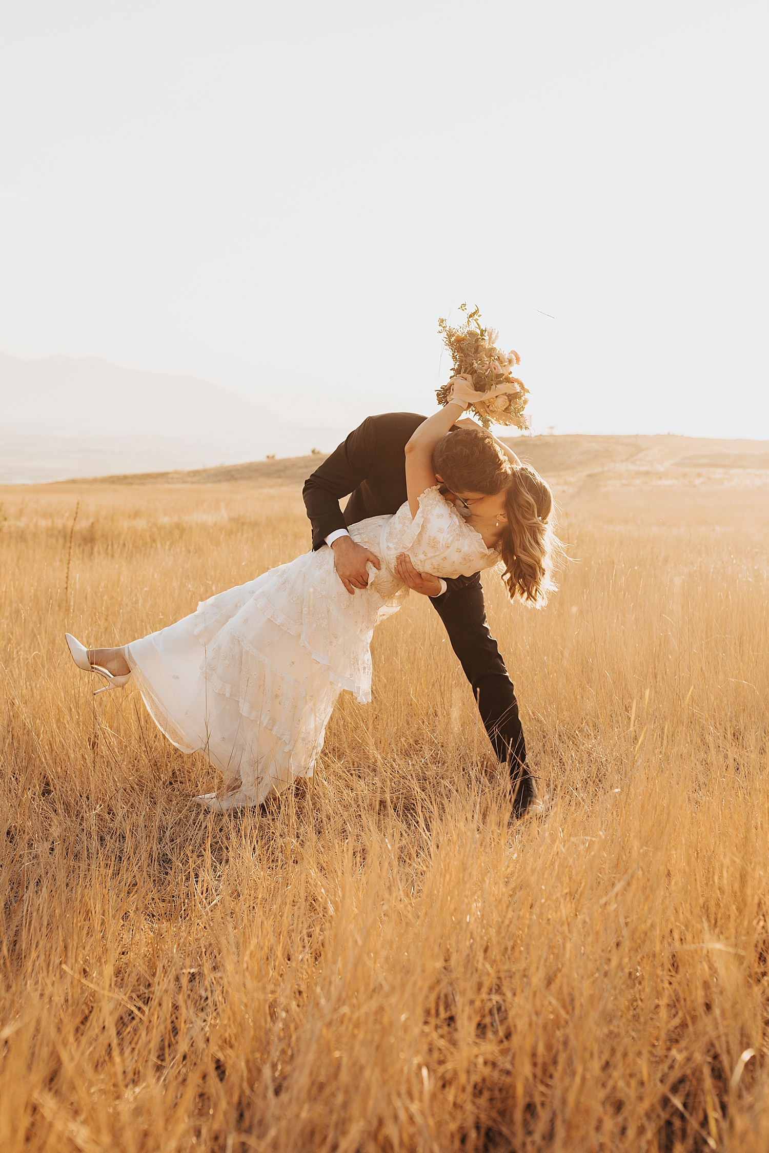 husband dips his wife for a kiss in big open field by Nicole Aston Photography