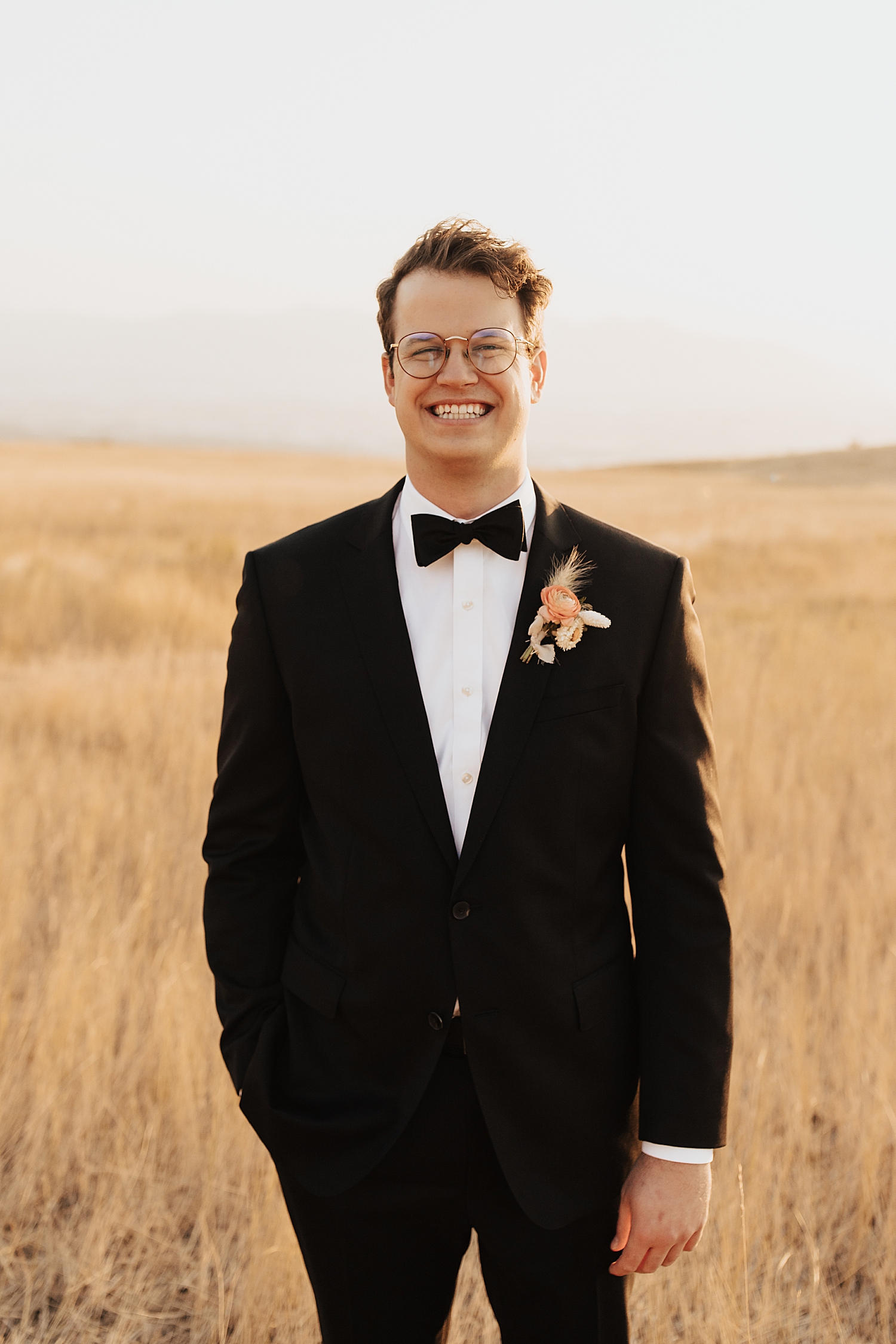 groom stands in a large empty field by Destination wedding photographer