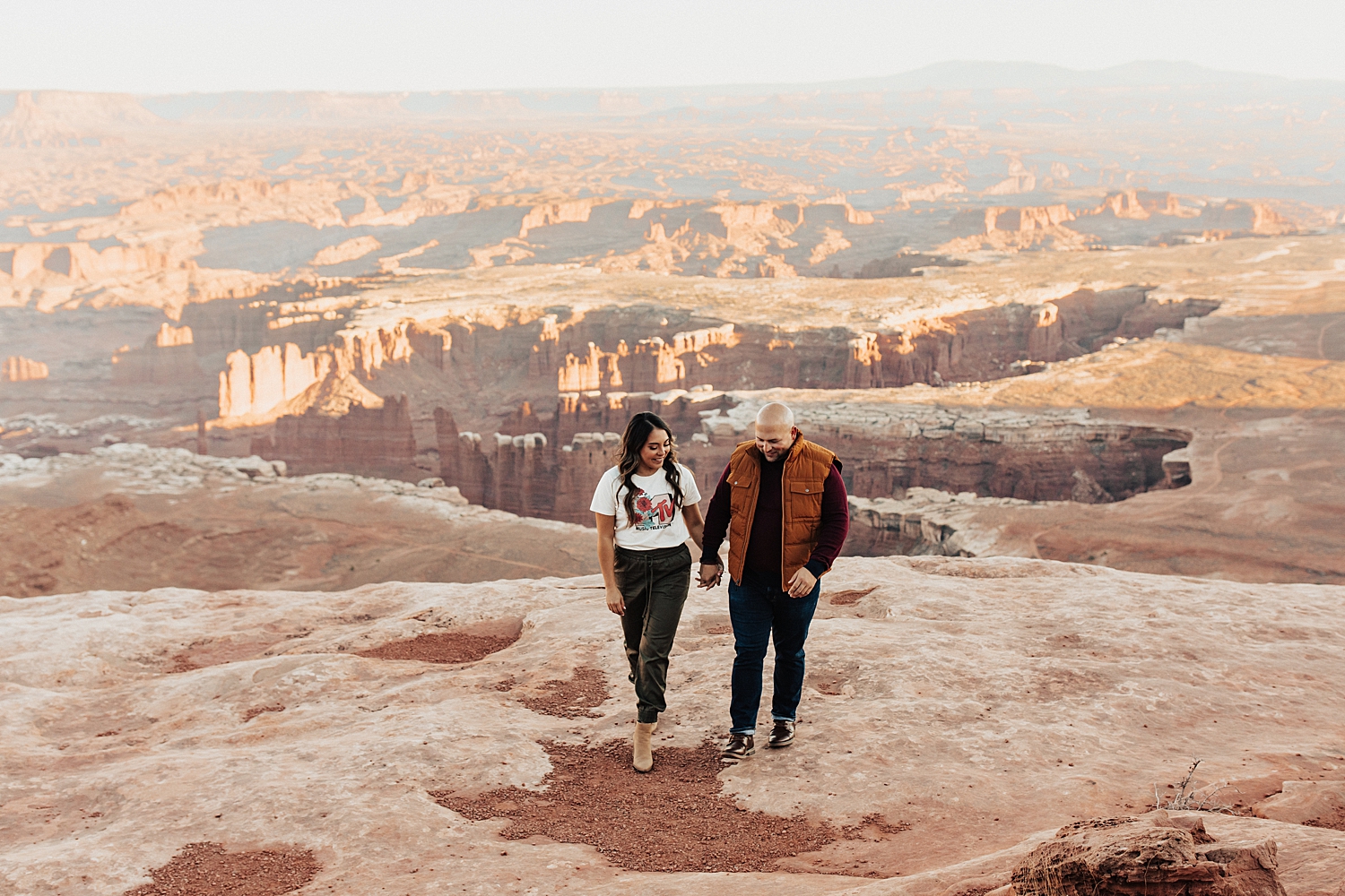 man and woman hold hands and walk near canyon by Destination wedding photographer