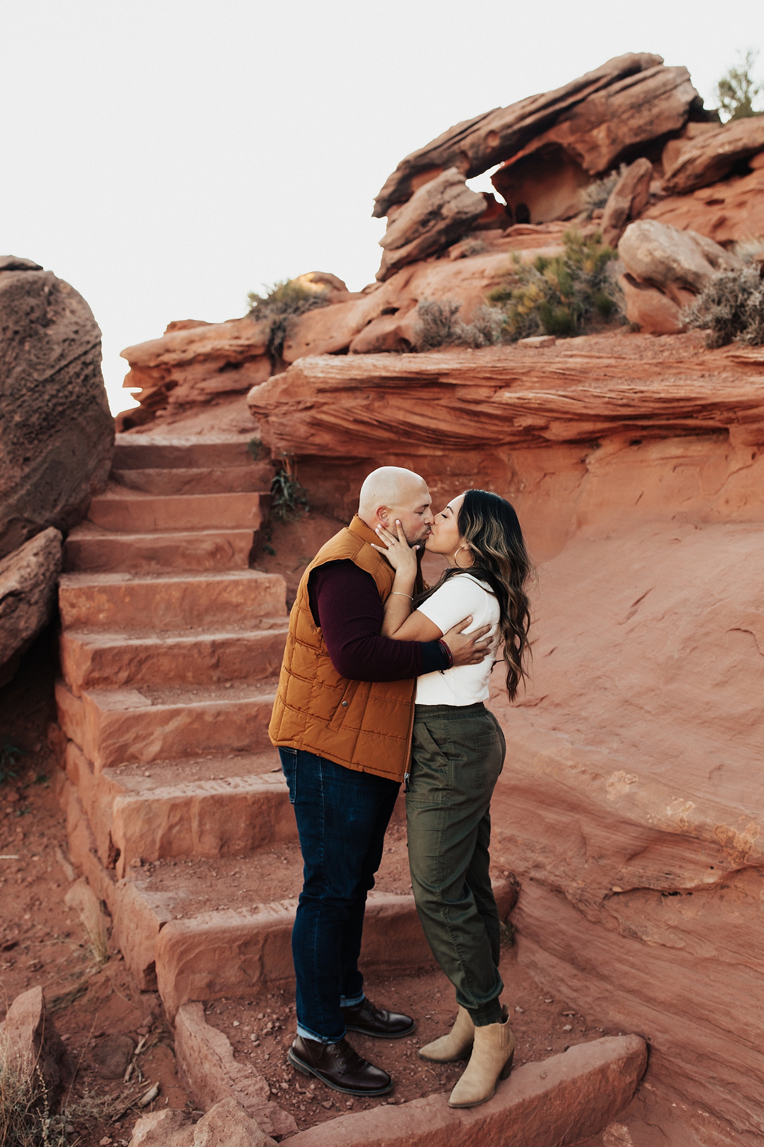 engaged couple share a kiss near red rock steps for Canyonlands National Park engagement session