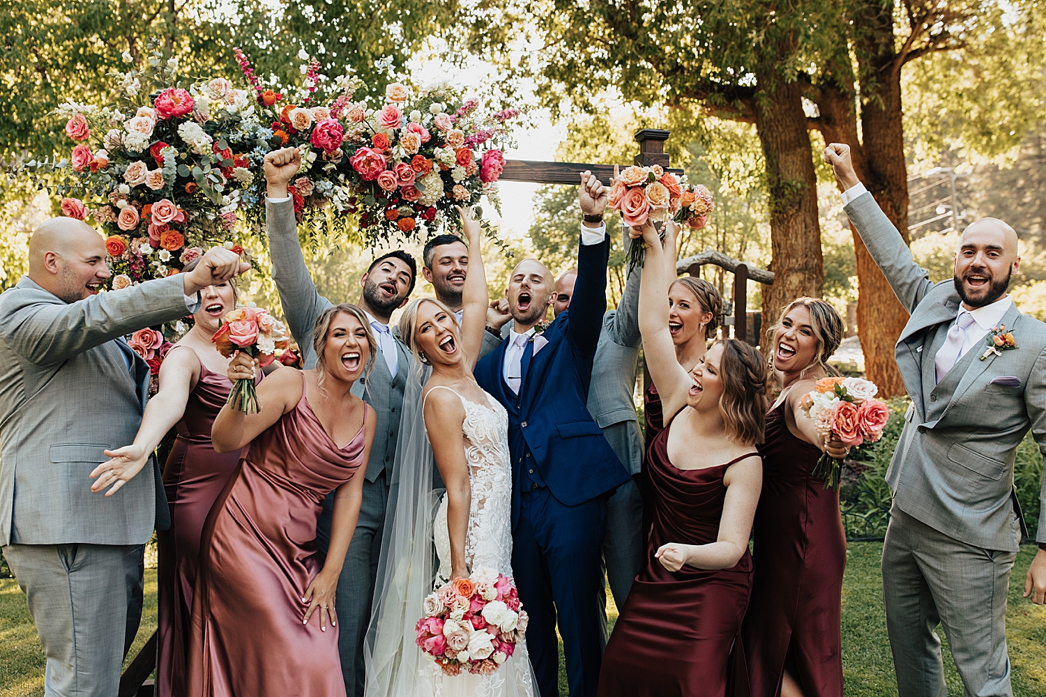 wedding party throws hands up in celebration around newlyweds by Nicole Aston Photography