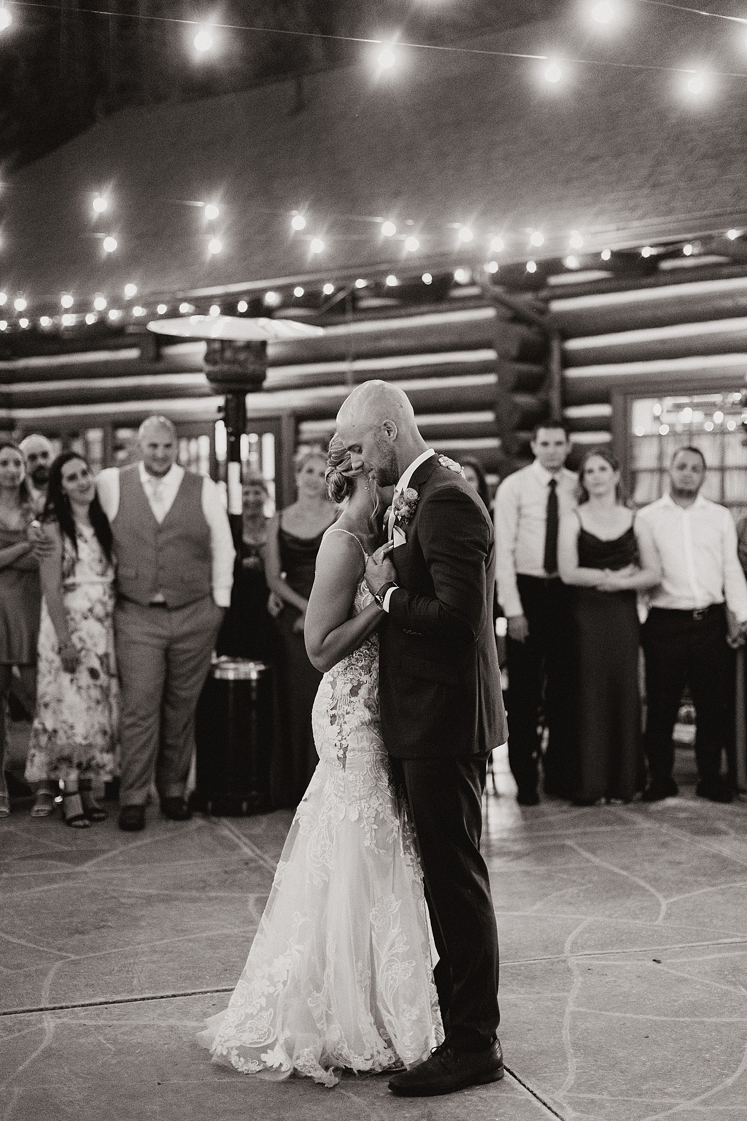newlyweds dance slowly under twinkle lights by Destination wedding photographer