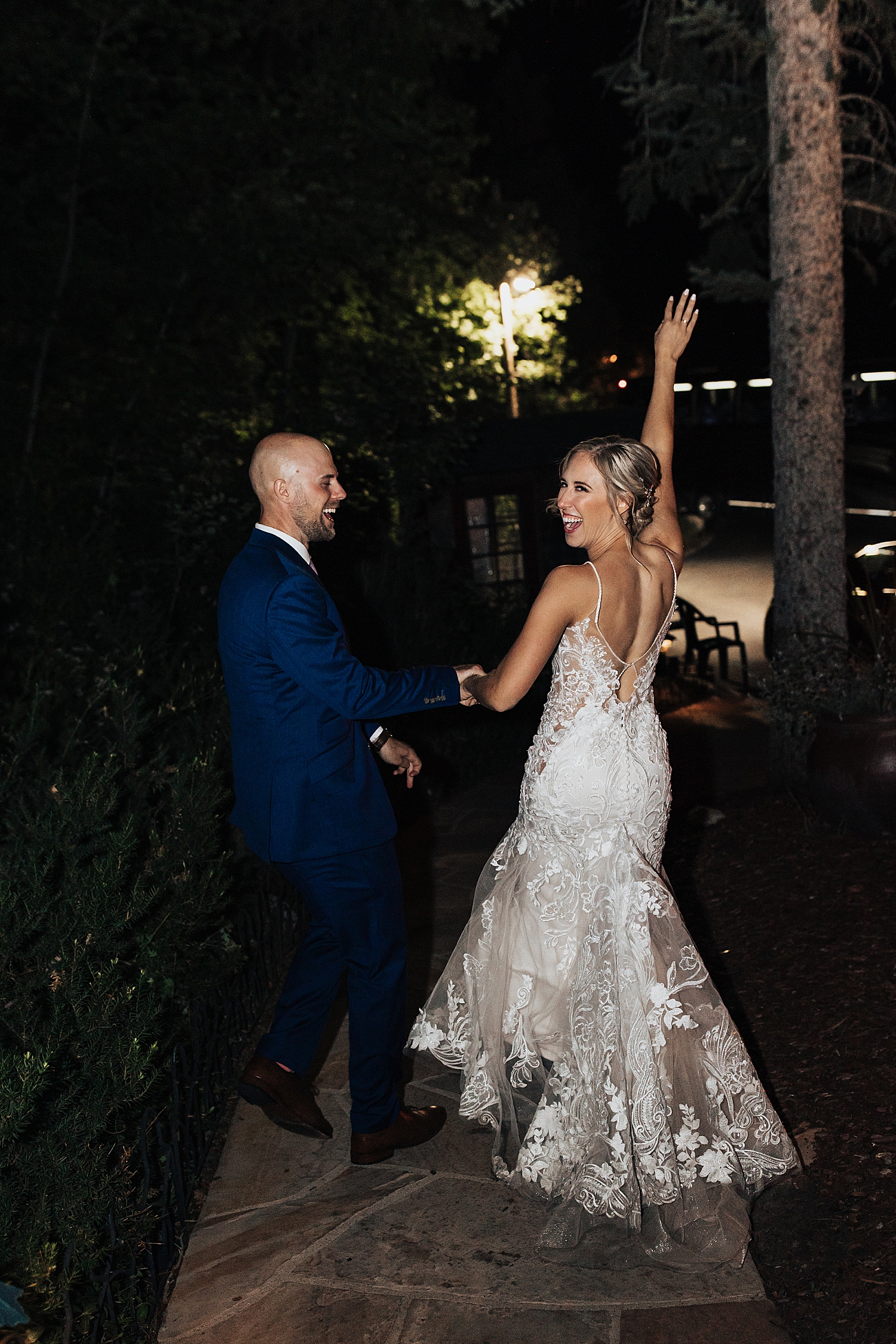 Bride lifts up her hand in celebration as they walk down sidewalk by Destination wedding photographer