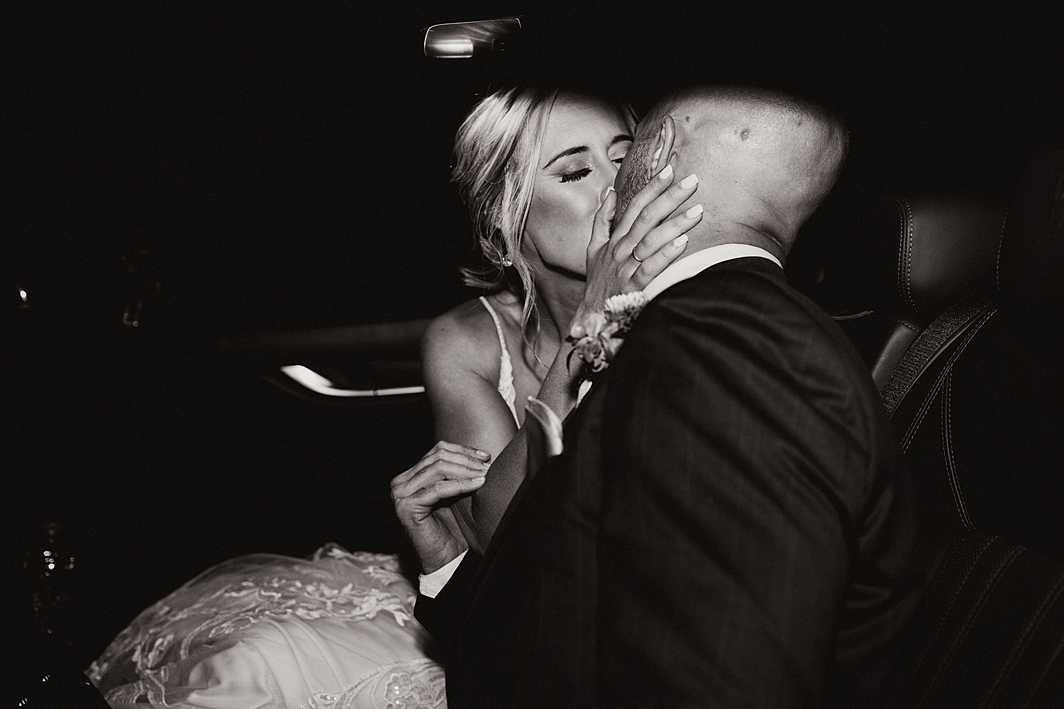newlyweds steal a kiss in the back of their getaway car by Nicole Aston Photography