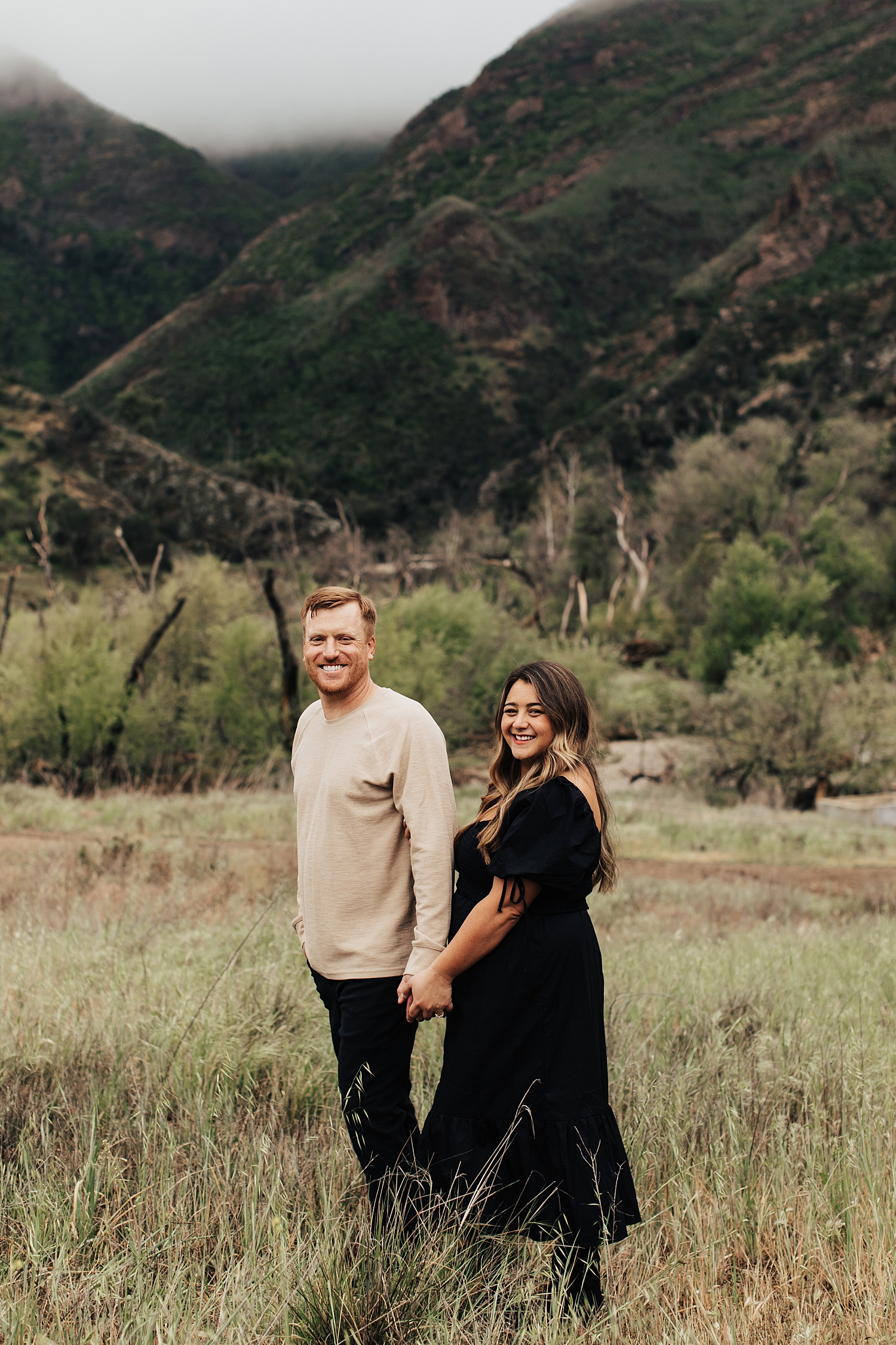 man and woman hold hands in front of mountain by Nicole Aston Photography