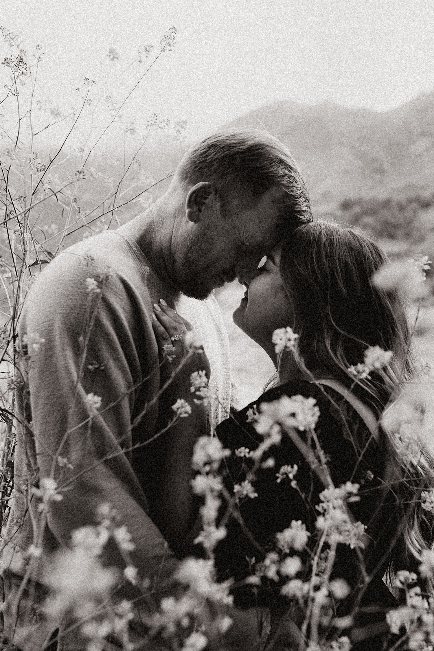 couple embrace behind flowers at Malibu Creek State Park