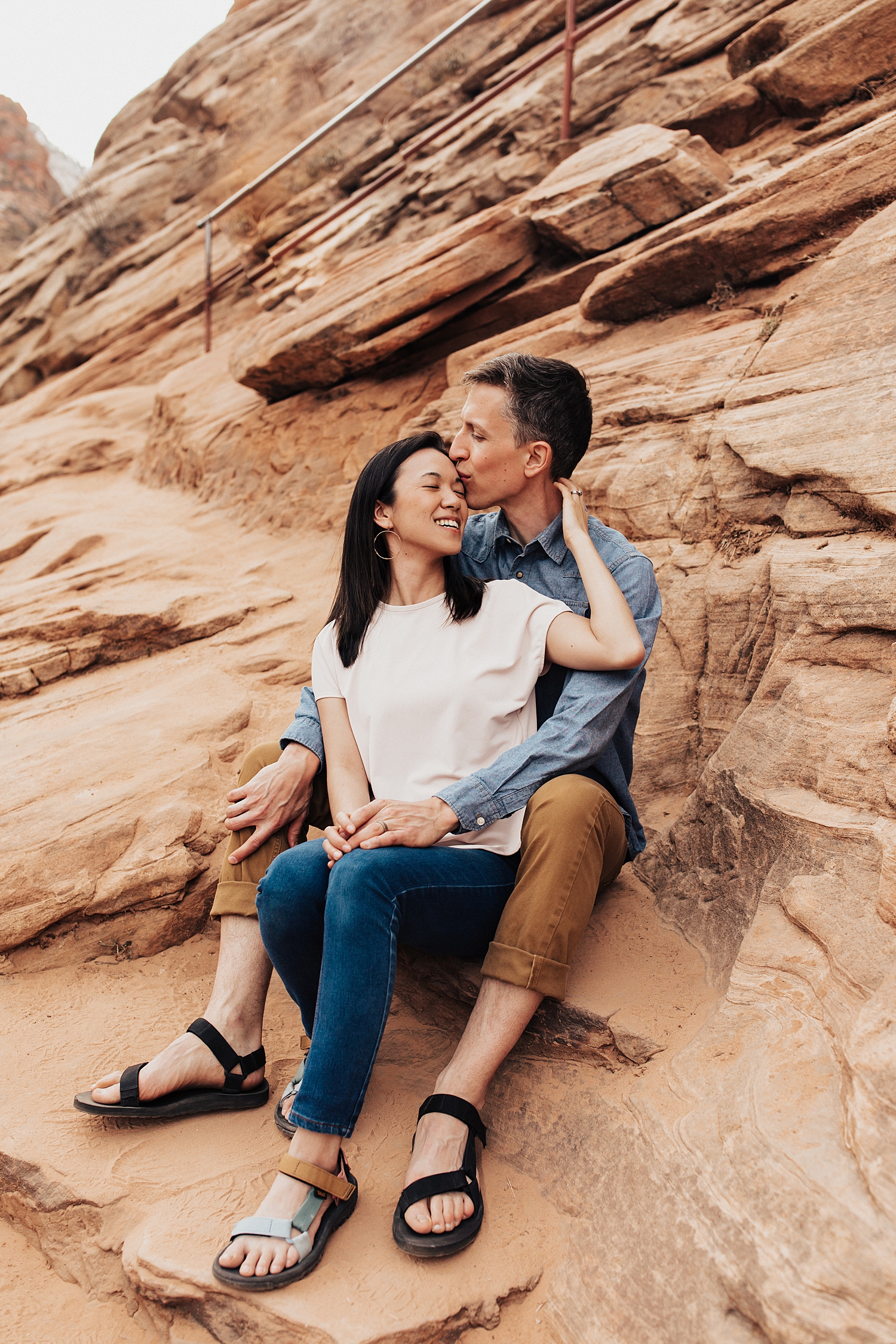 man and woman sit on red reds snuggling close by Nicole Aston Photography