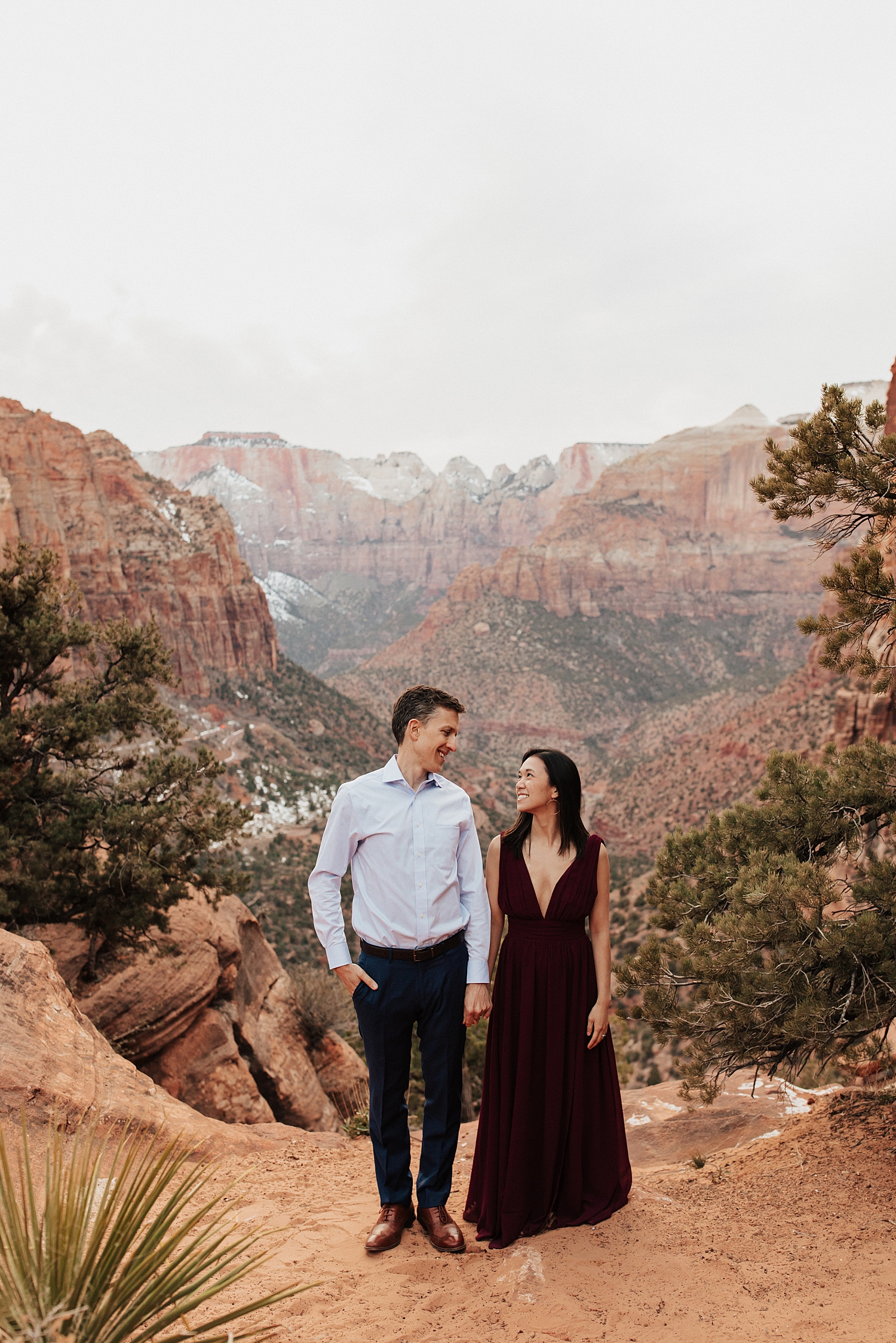man and woman hold hands on cliffside at Zion National Park