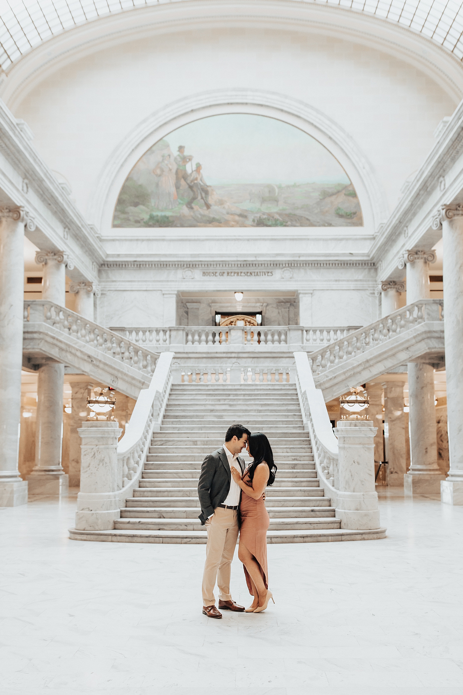 man and woman stand at the foot of stairs for Capitol Building engagement session