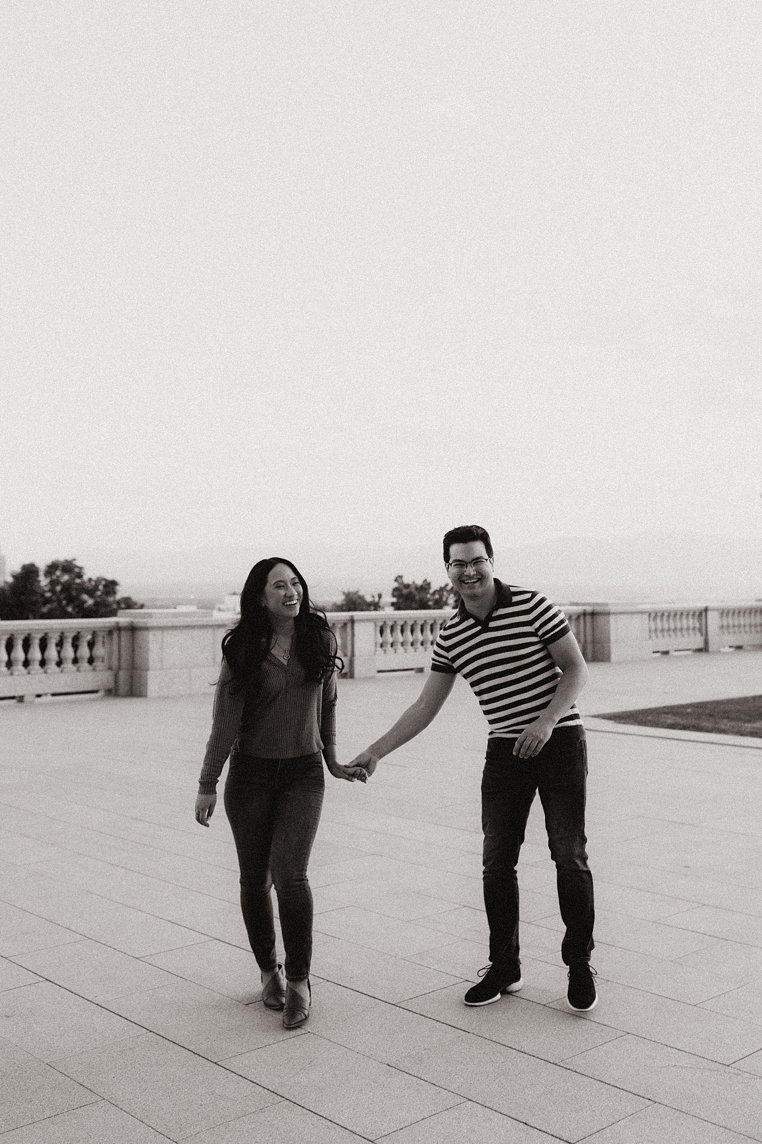 couple hold hands walking across a balcony by Destination wedding photographer