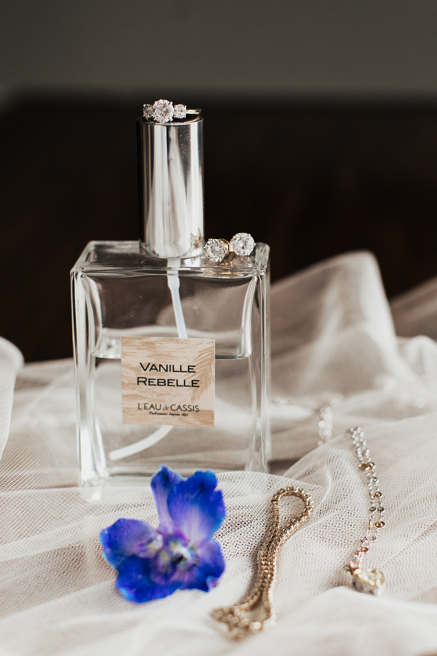 perfume bottle next to jewelry on veil by Destination wedding photographer