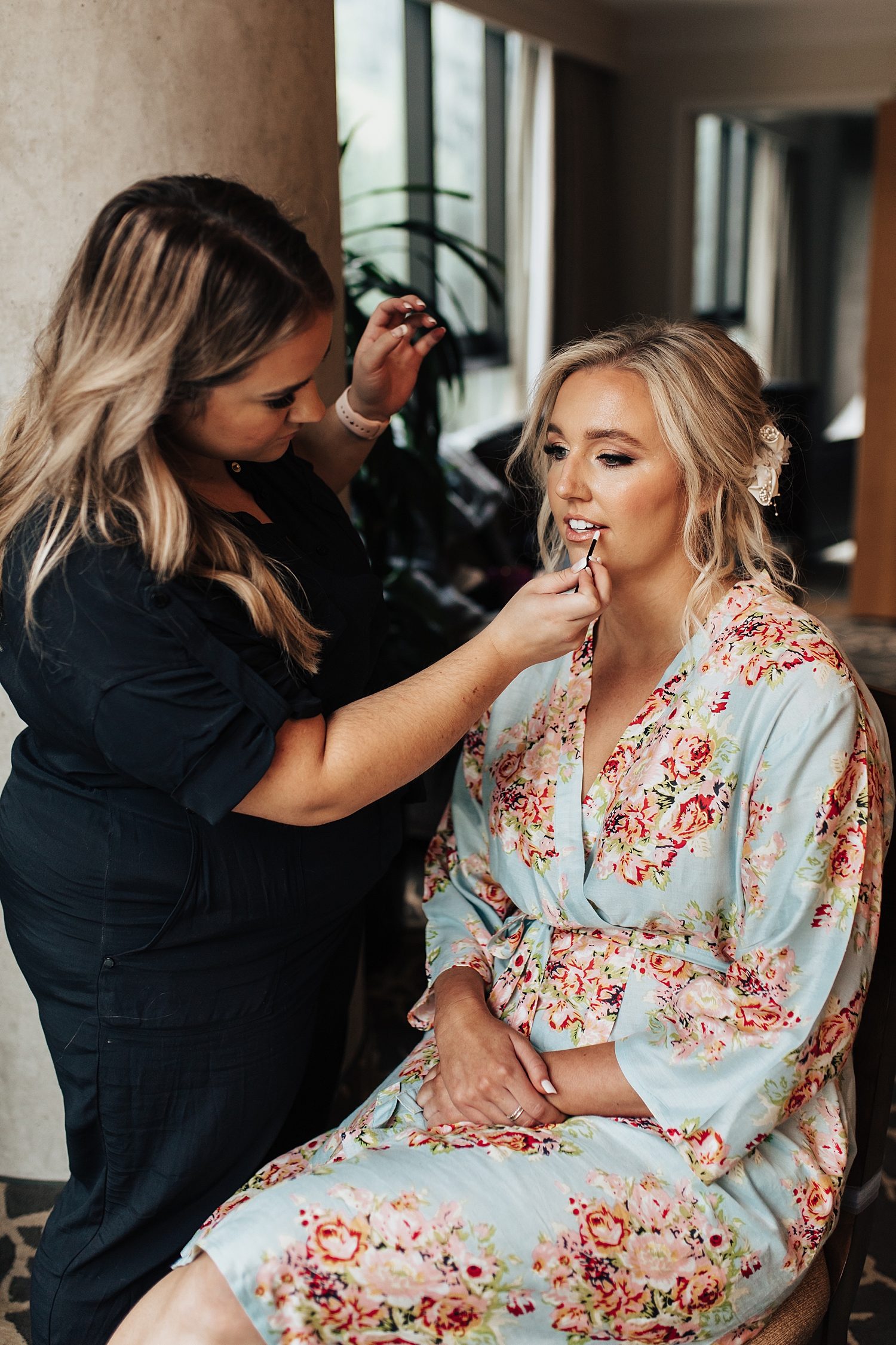 blonde bride in colorful robe gets makeup done before ceremony at Snowbird Mountain