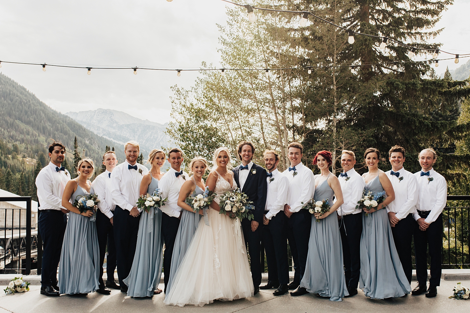 wedding party in light blue and black surround the newlyweds outside by Nicole Aston Photography