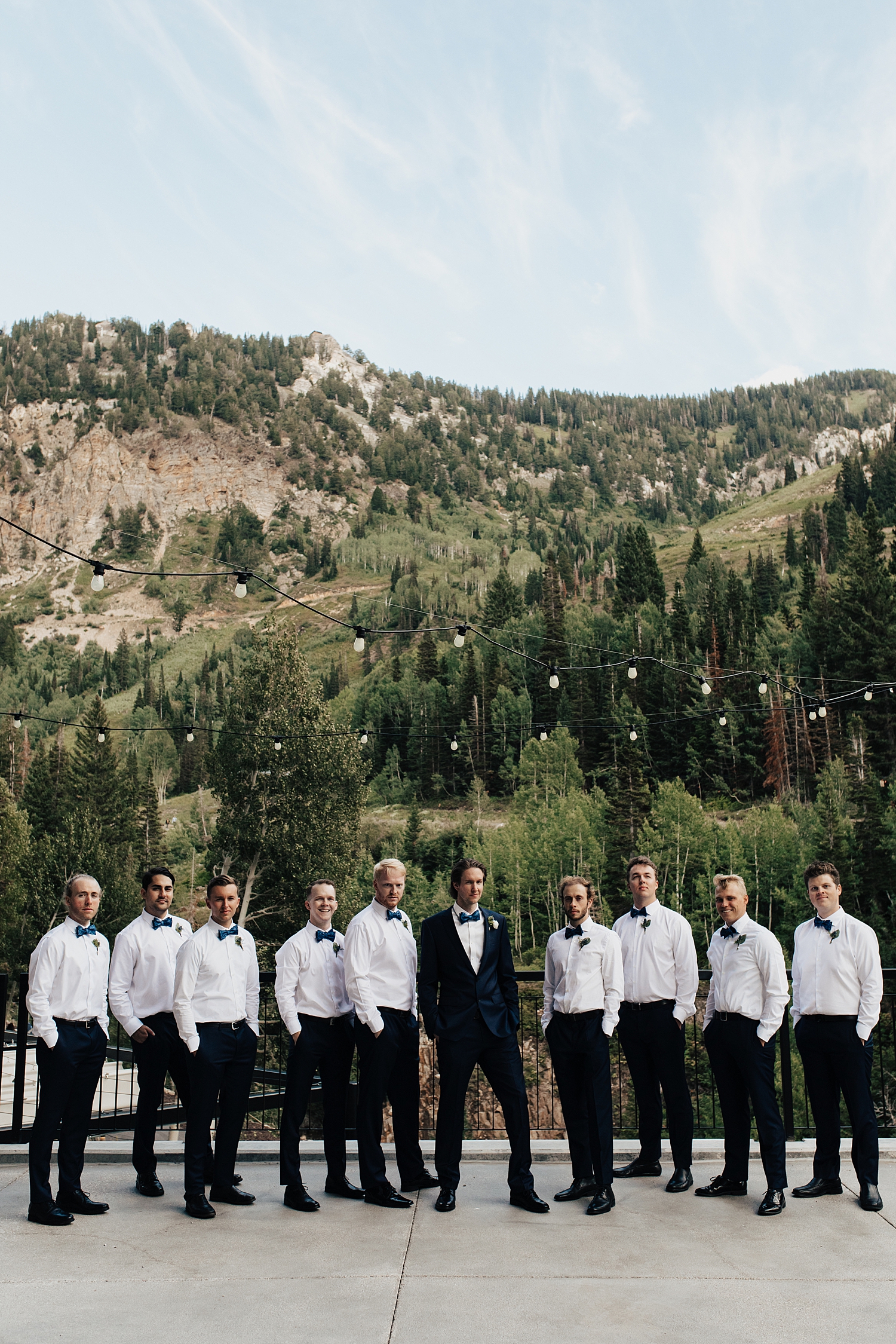 groomsmen stand around groom with epic backdrop at Snowbird Mountain
