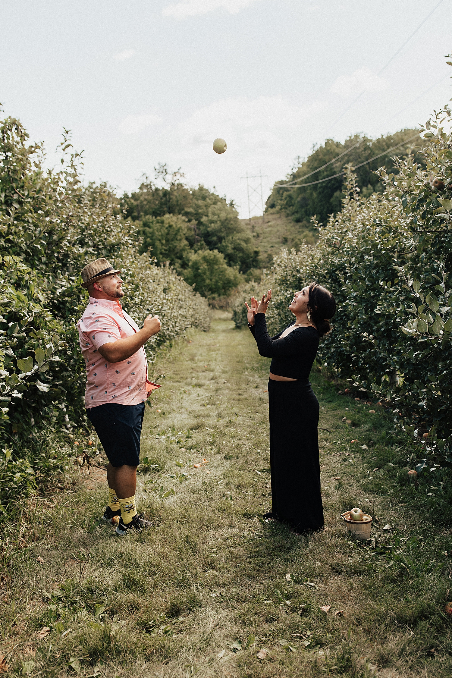 couple throws apple in air in orchard for Iowa wedding weekend