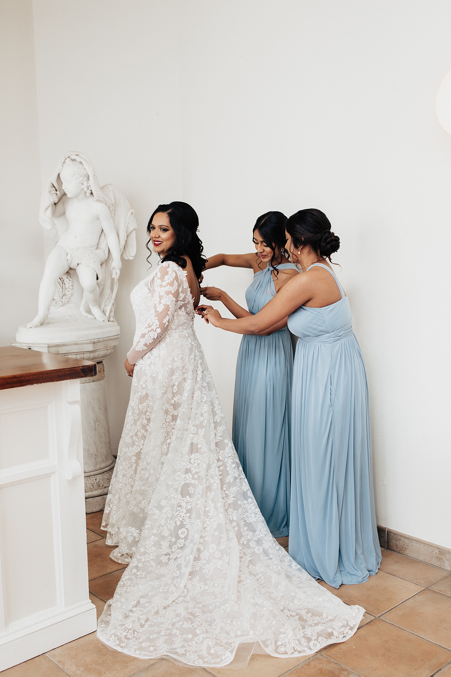 bridesmaids in blue help with zipper by Nicole Aston photography
