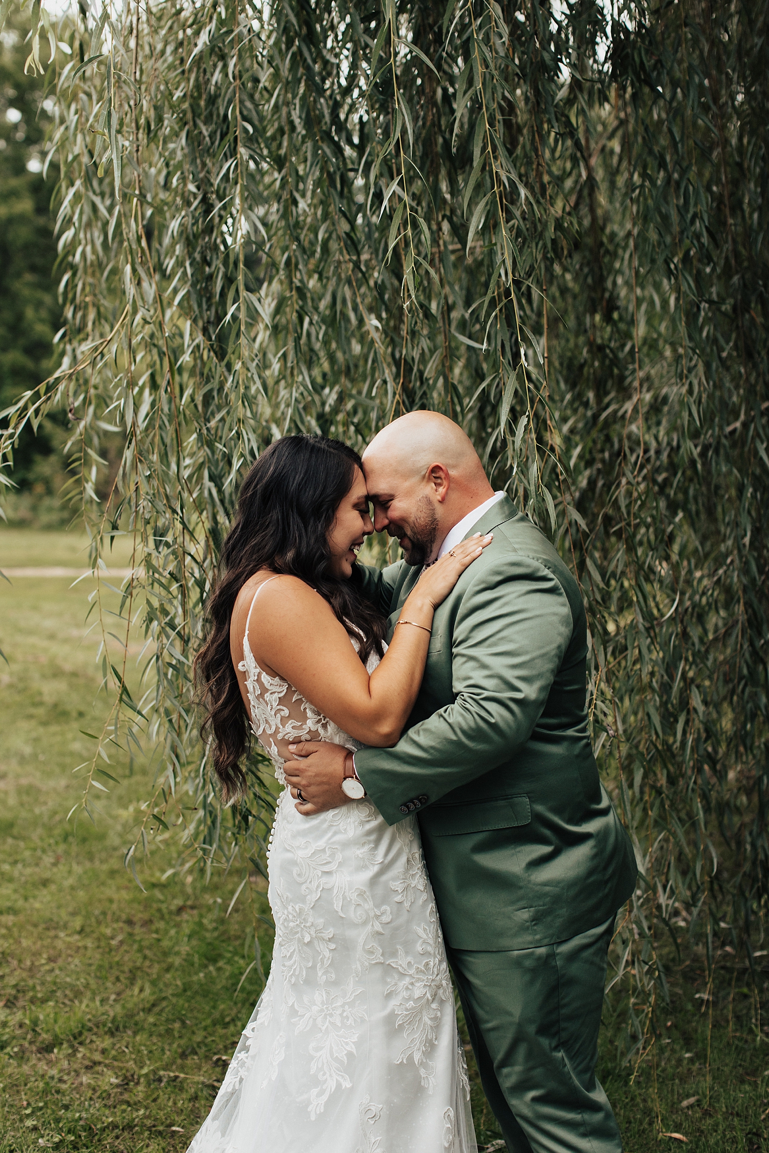 couple embraces in front of a willow tree by Destination elopement photographer