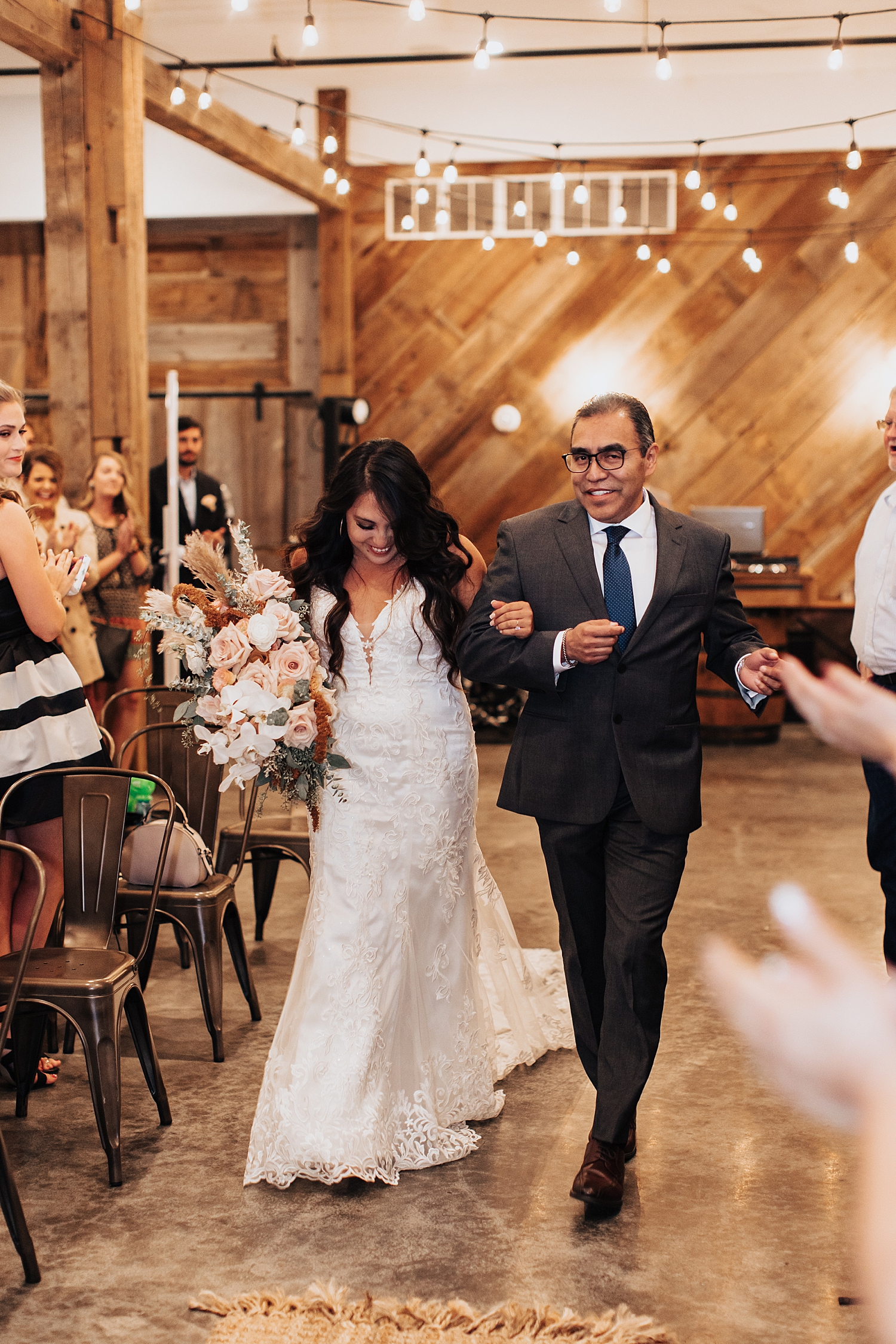 woman walks down indoor aisle with dad for Iowa wedding weekend