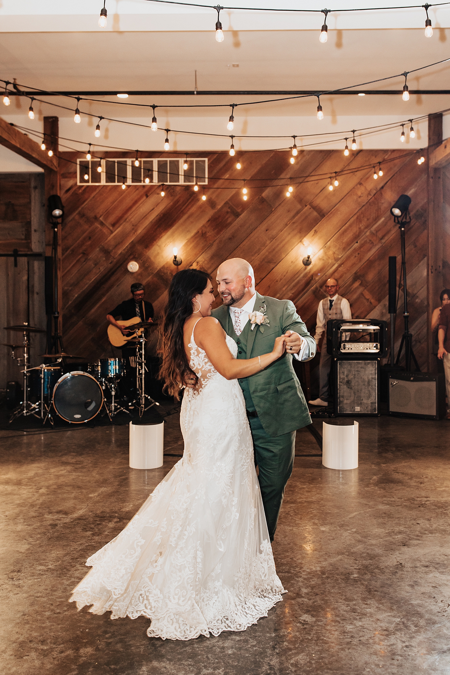 man in green suit dances with his bride under twinkle lights by Nicole Aston Photography