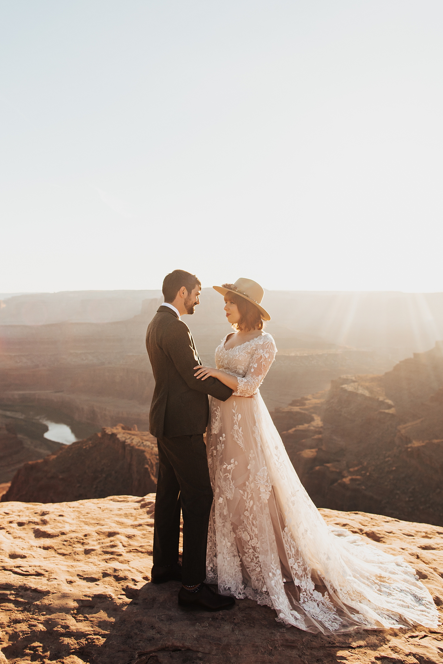 couple hold each other close with sweeping canyons behind them by Destination wedding photographer