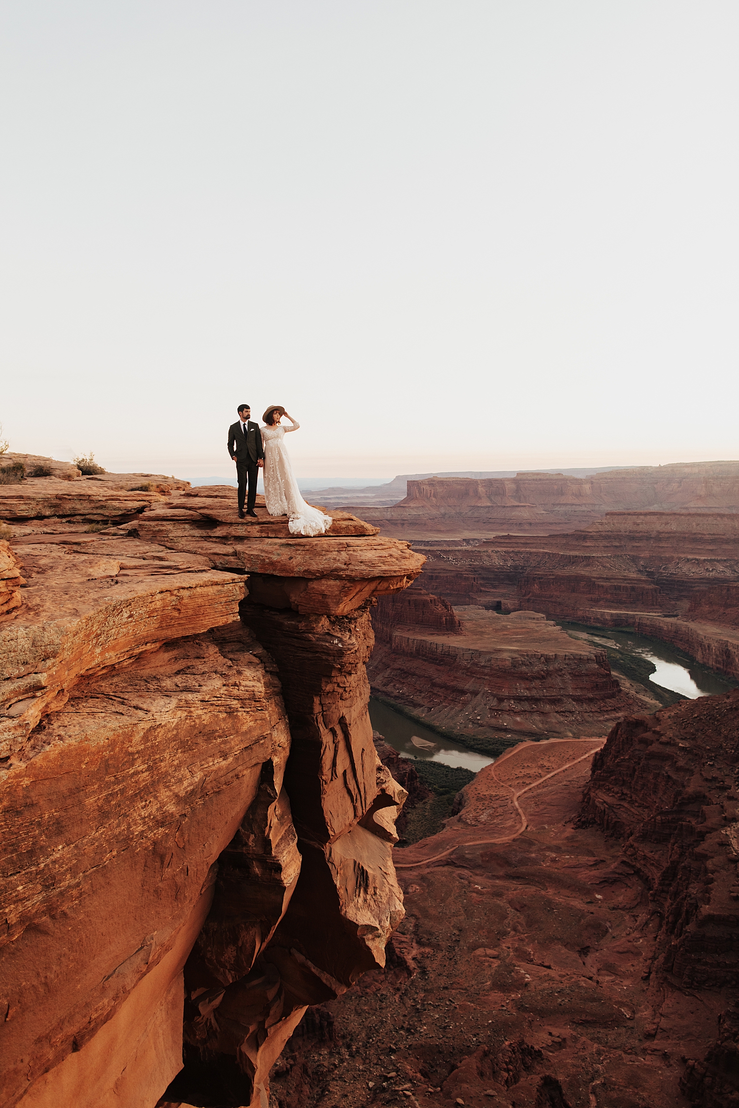newlyweds stand on cliffside overlooking canyons by Nicole Aston Photography