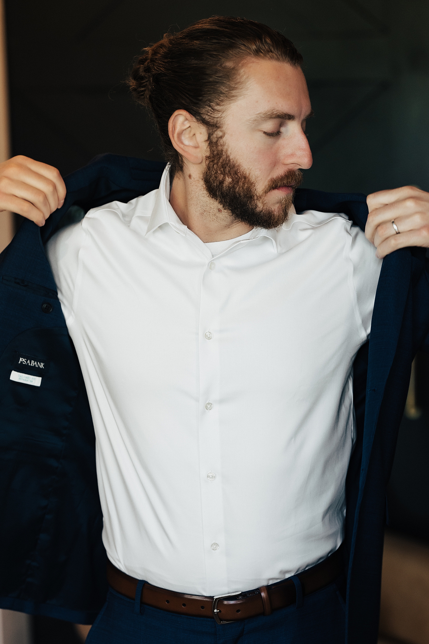groom puts on his jacket before ceremony at River Bottom Ranch venue