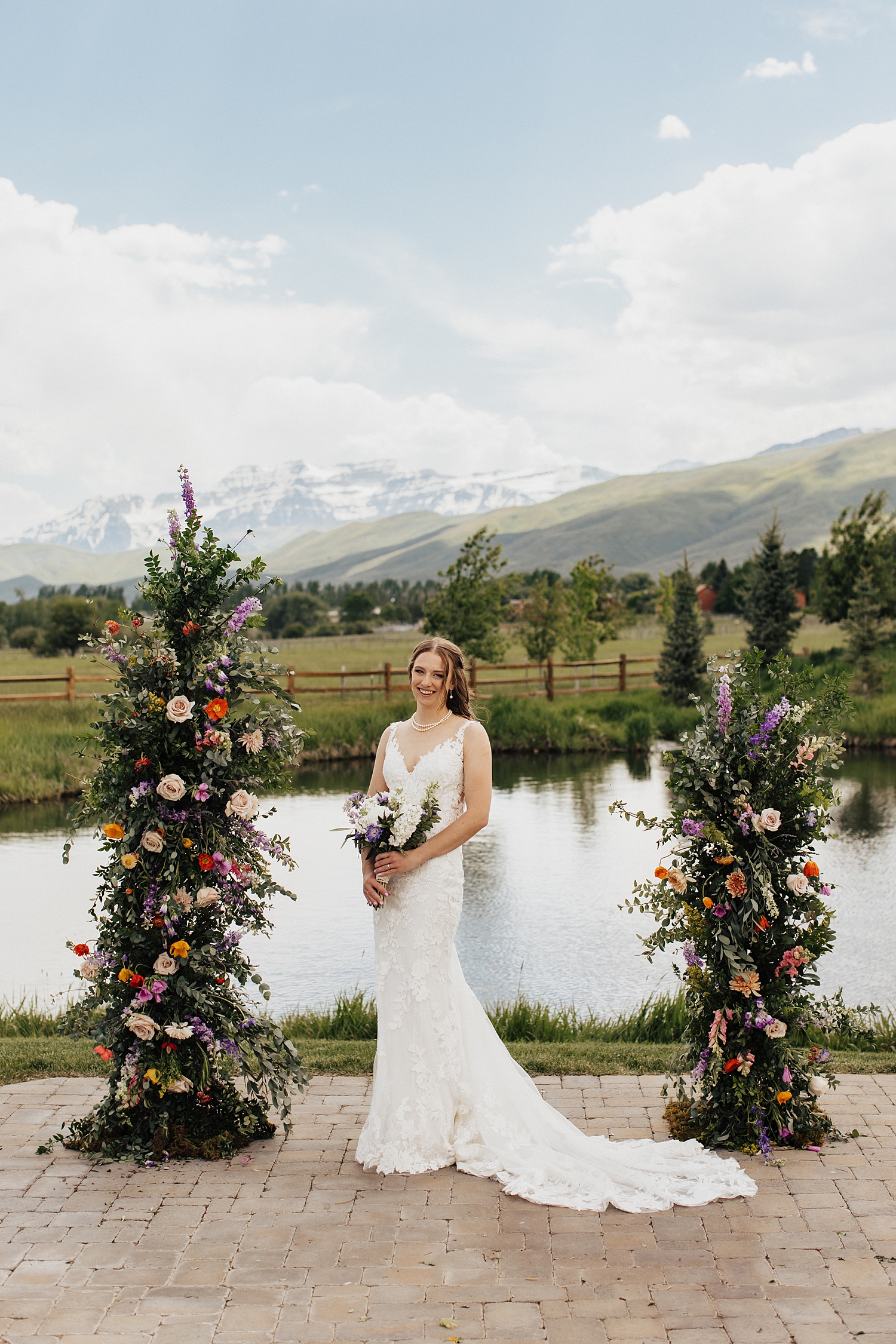 bride stands in front of floral arch by Nicole Aston photography