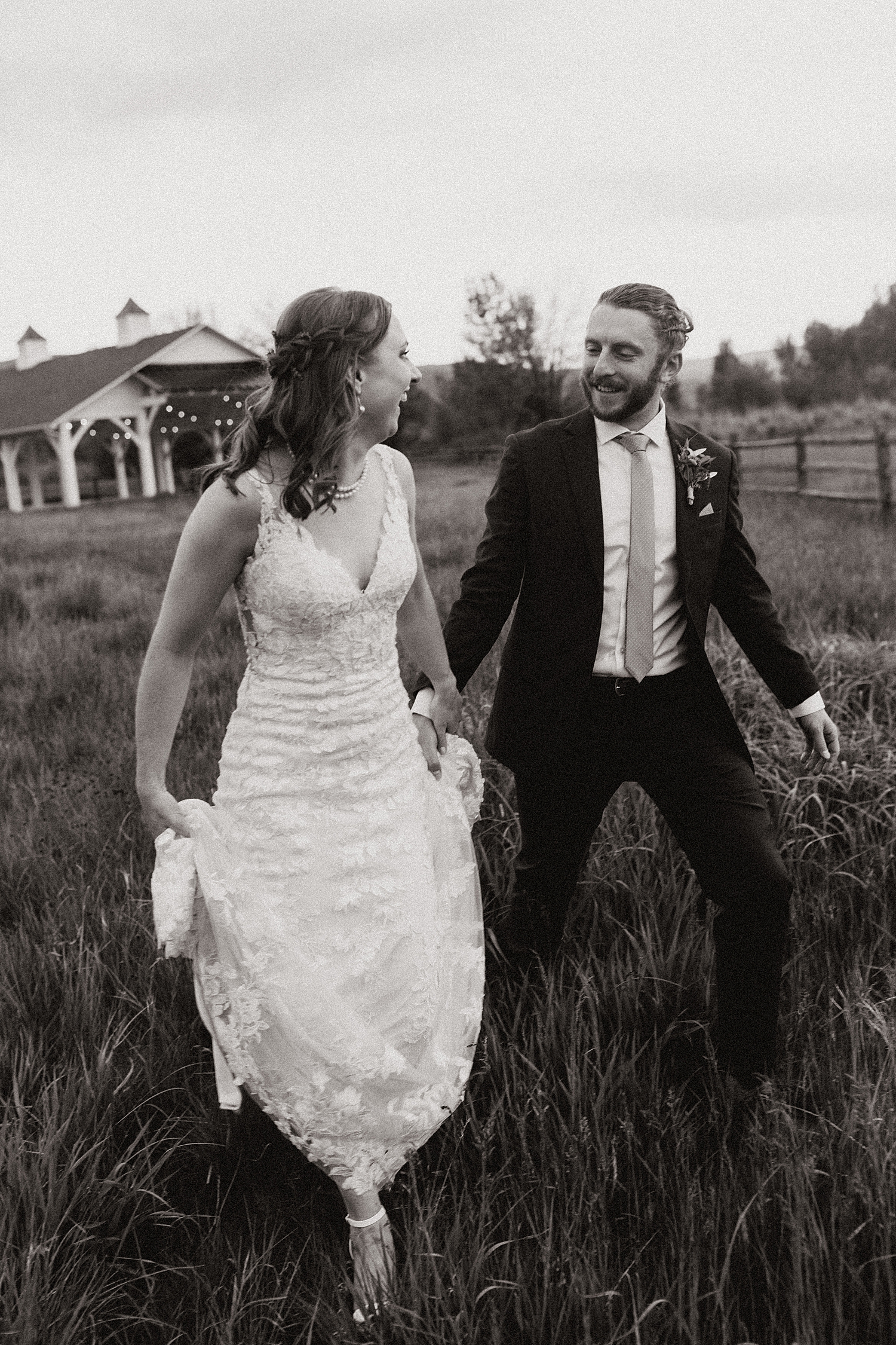 newlyweds laugh and run through field at River Bottom Ranch venue