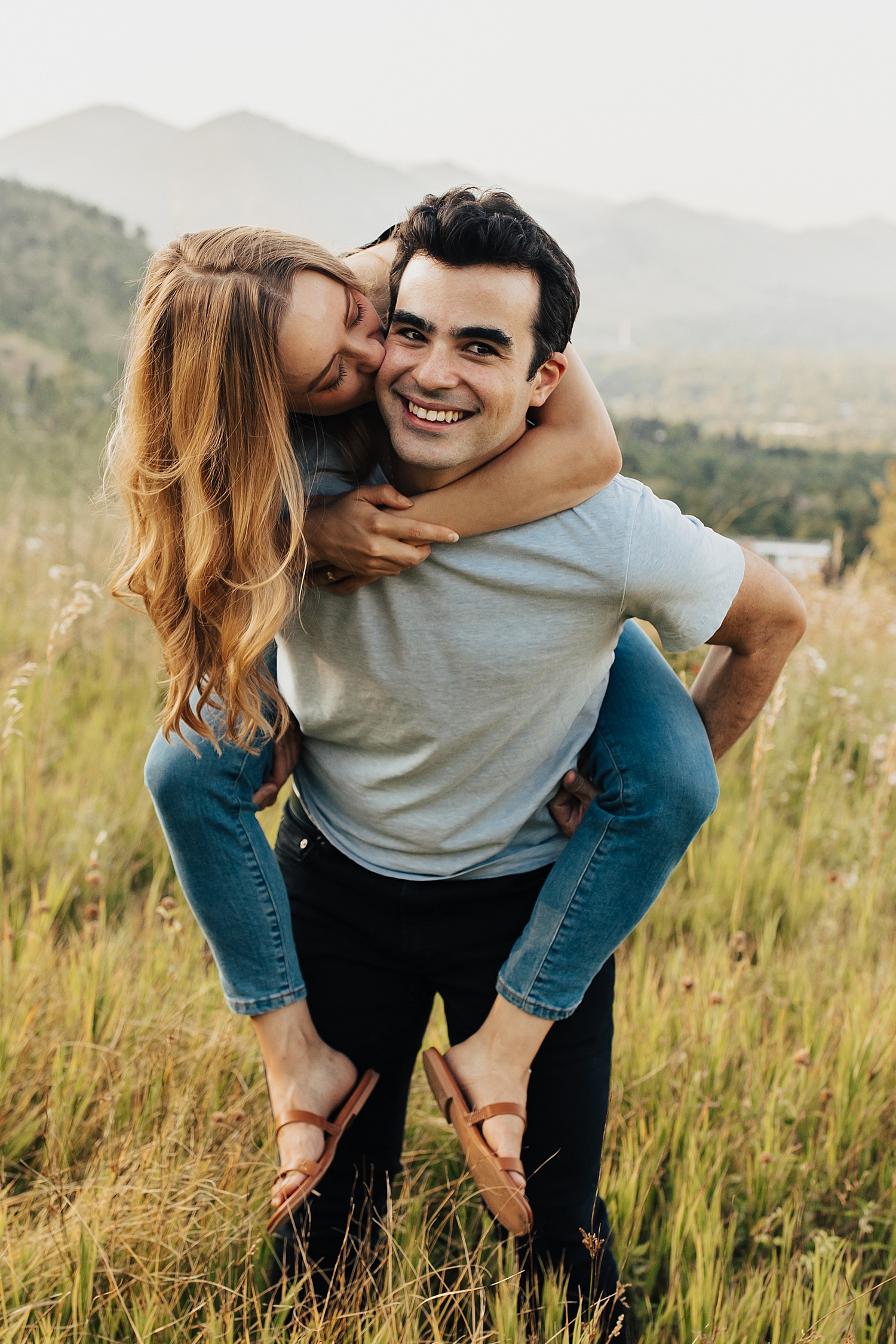 woman hops on her man's back for engagement session at the Flatirons