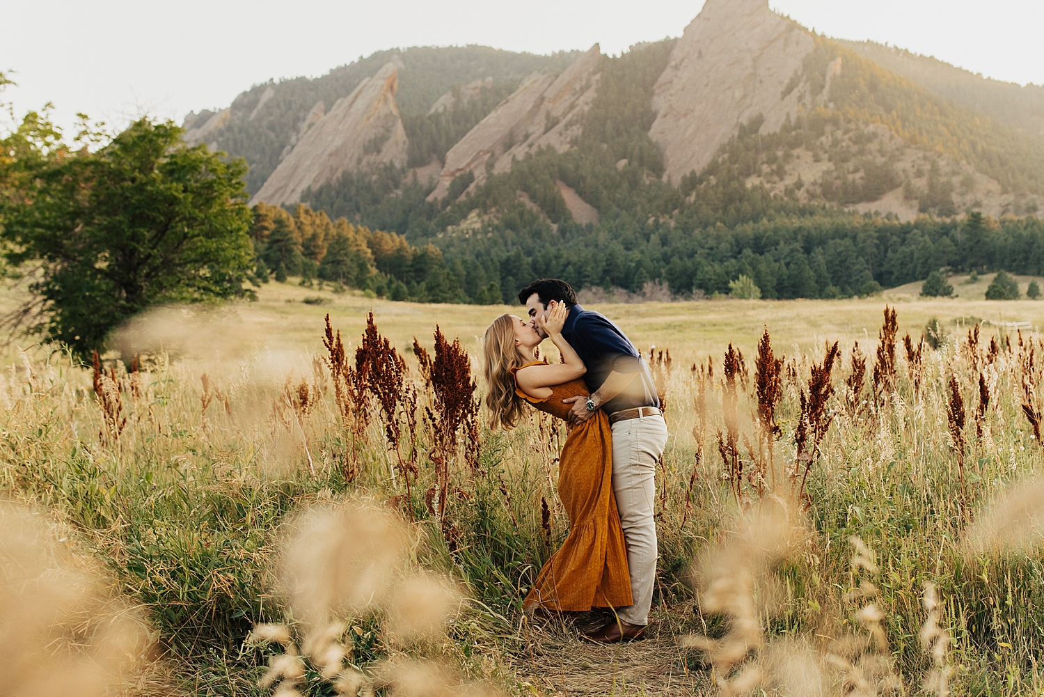 man leans woman down to kiss her in big field by Destination wedding photographer