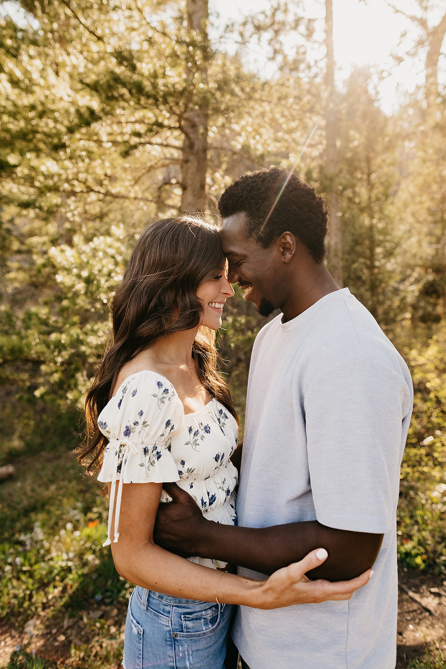 engaged couple hold each other under the tall trees by destination wedding photographer