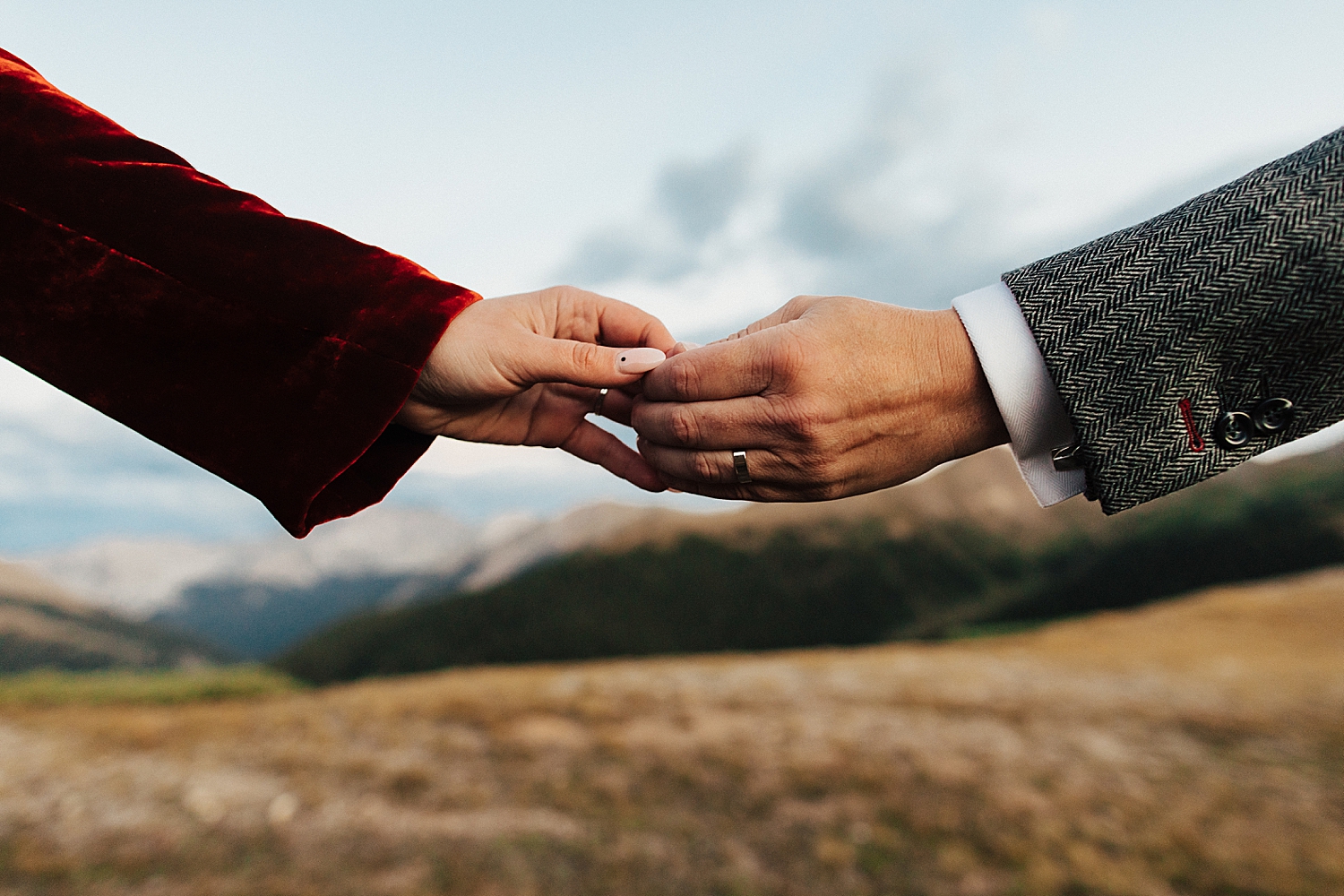 man and woman's hand gripped across mountain views by destination wedding photographer