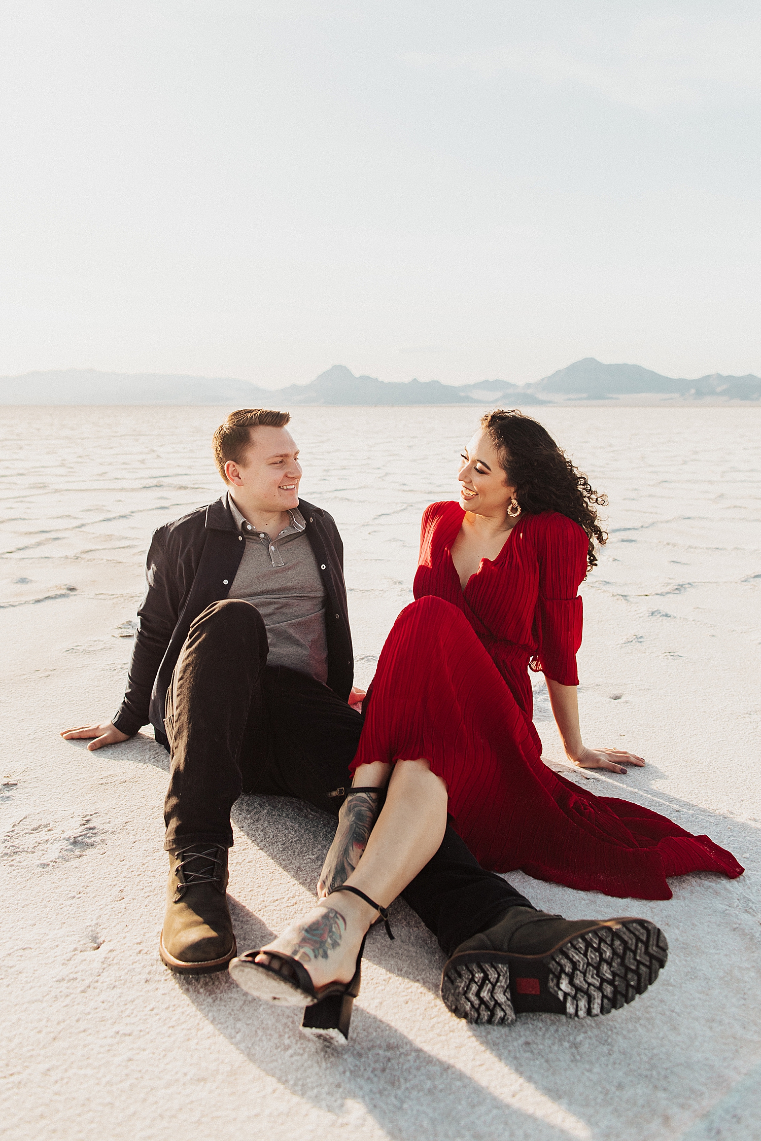 couple sit together on desert ground for Salt Flats Engagement Session