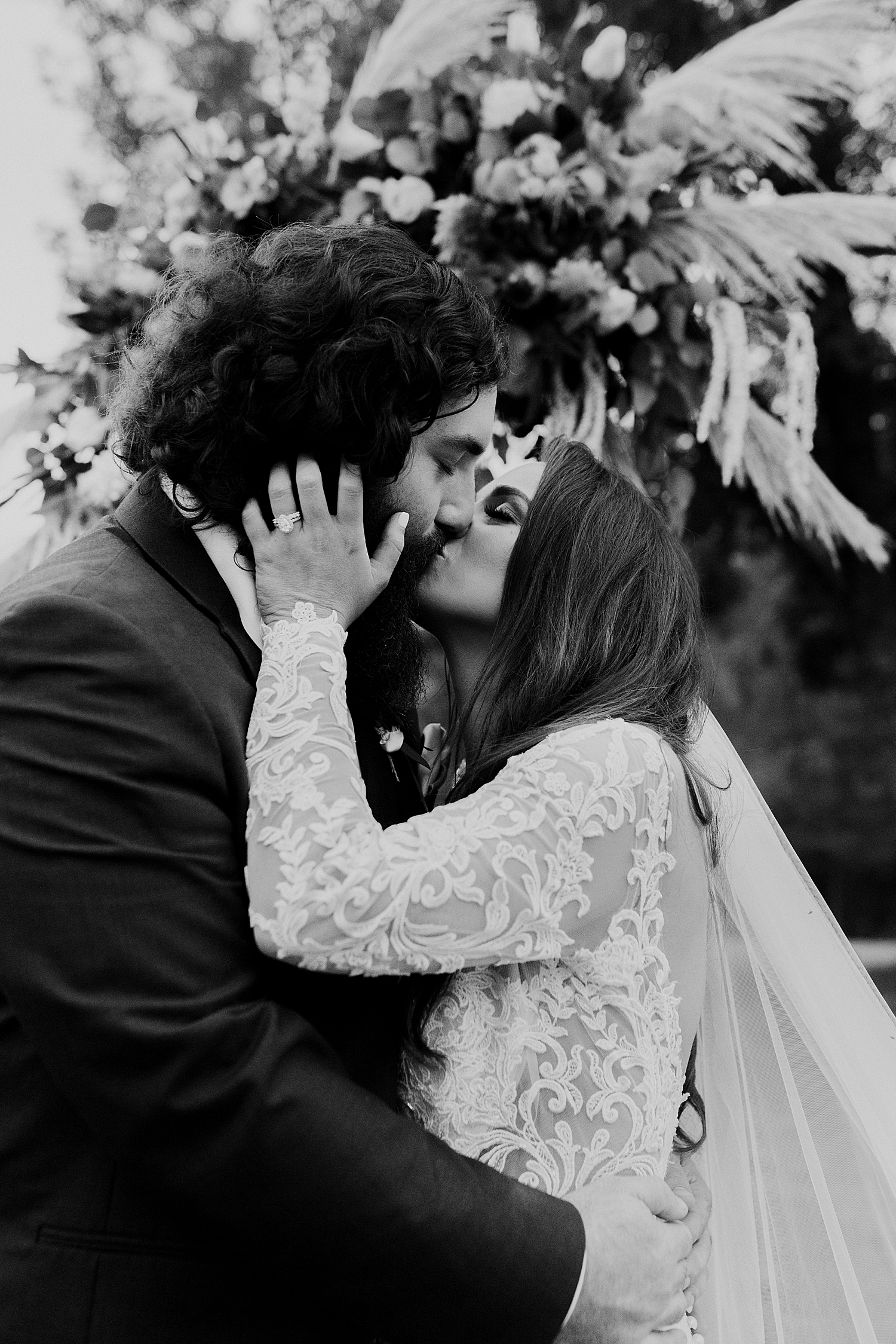 couple kiss beneath florals at Southern Backyard Wedding
