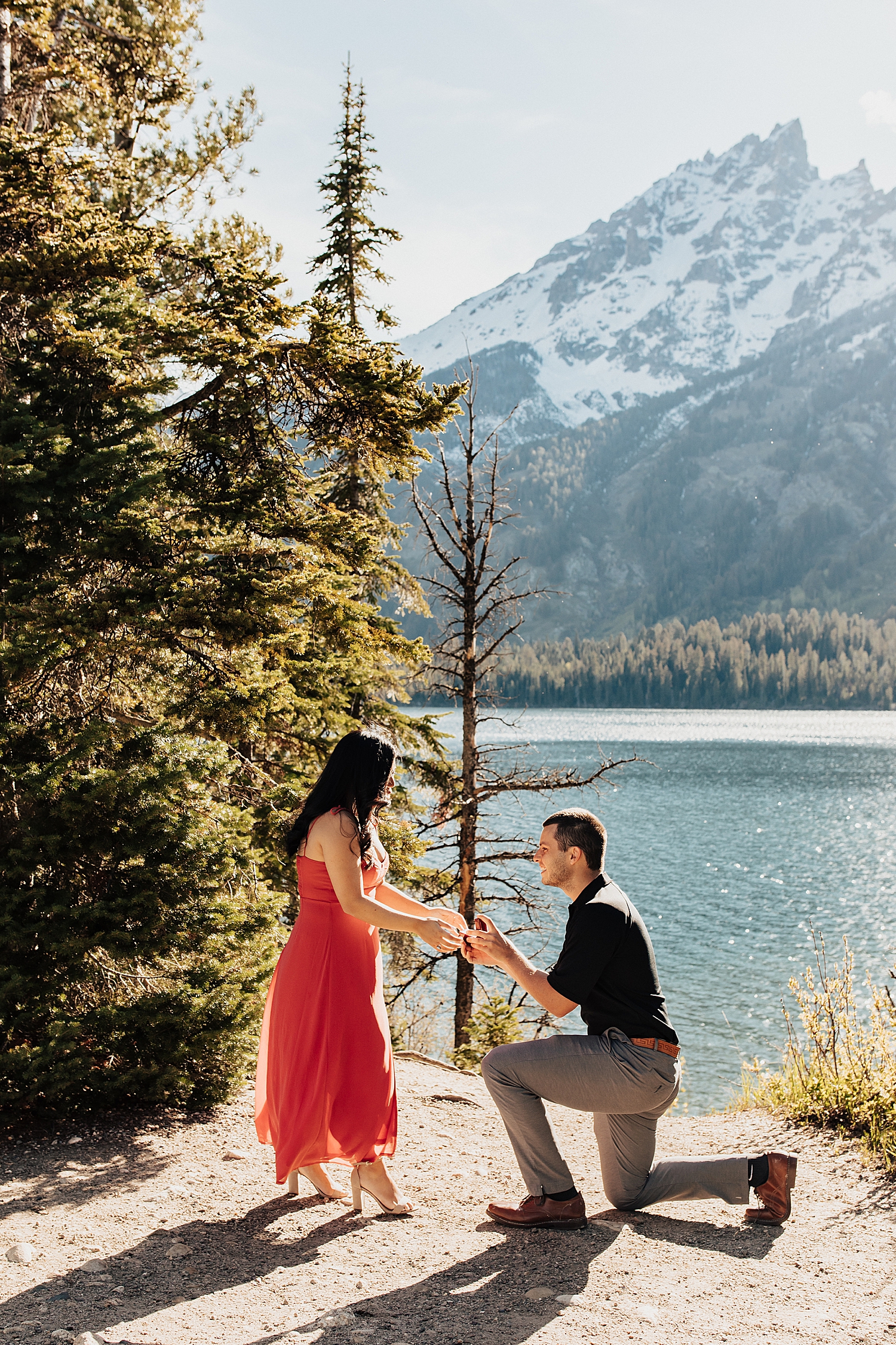 man proposes on one knee in front of lake by Nicole Aston Photography