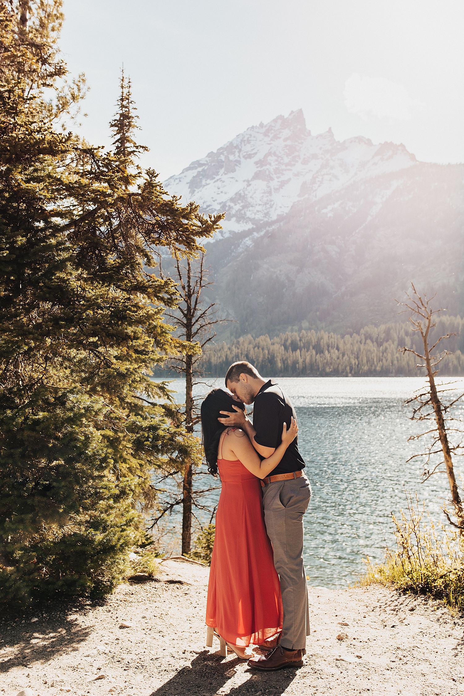 newly engaged couple share a kiss in front of mountain at Grand Tetons National Park