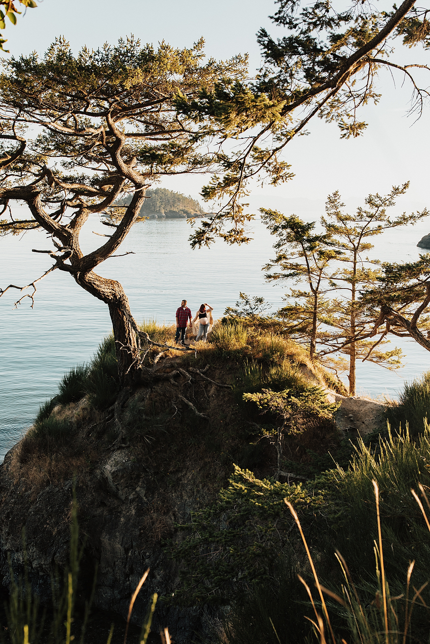 pregnant woman and her husband on cliffside overlooking ocean by destination photographer